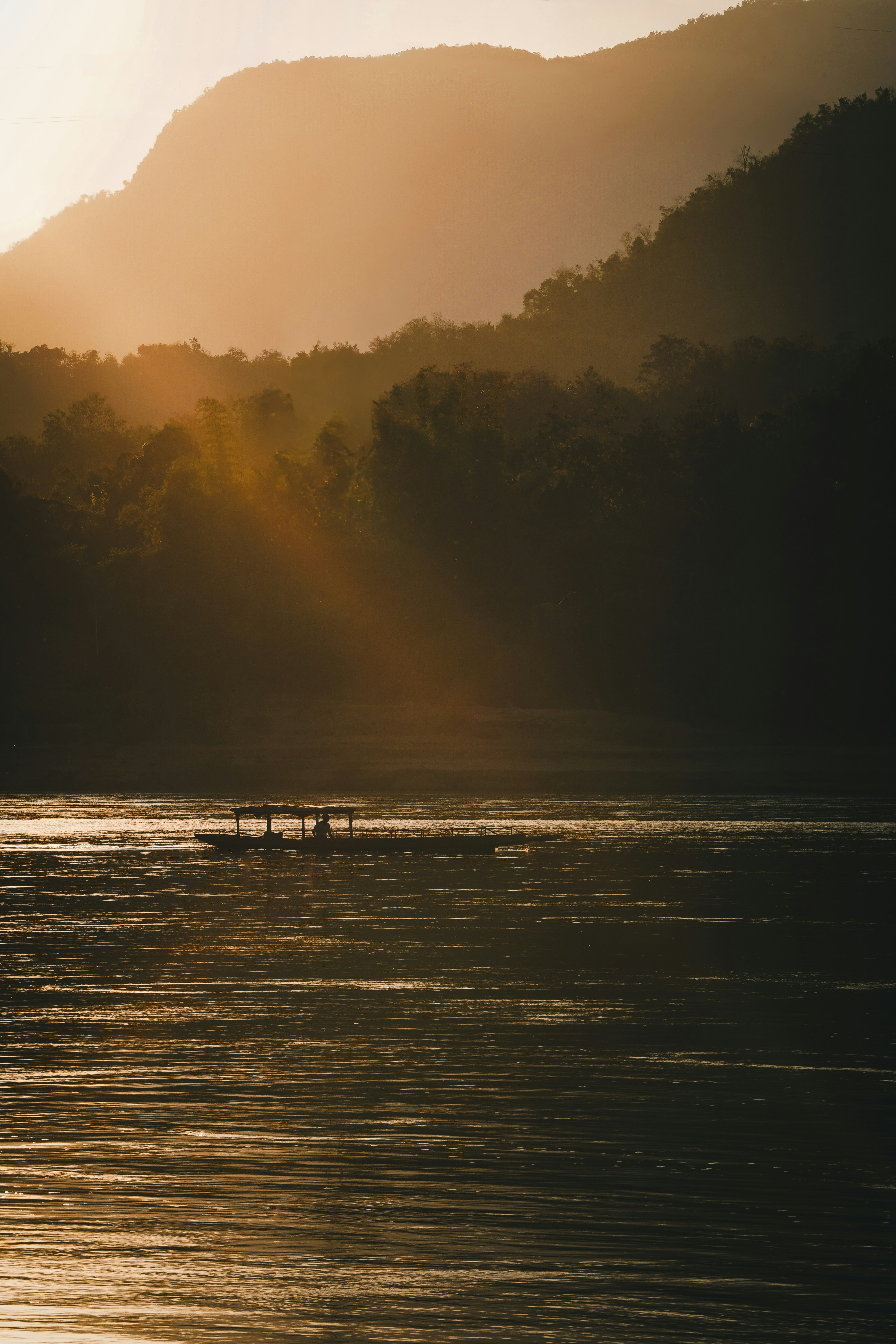 A boat sails on a river at sunset.