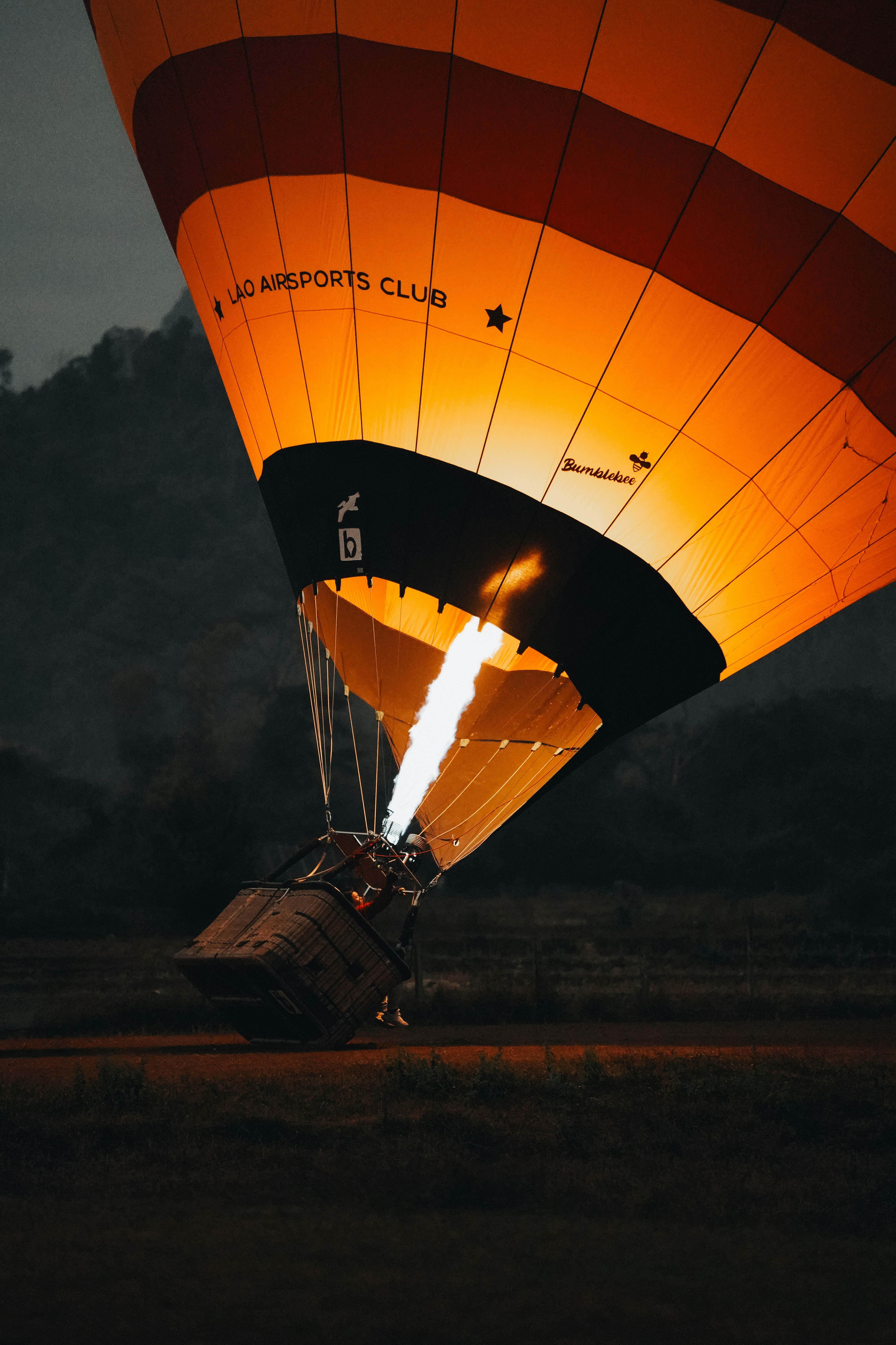 Hot air balloon inflates with flame at dusk