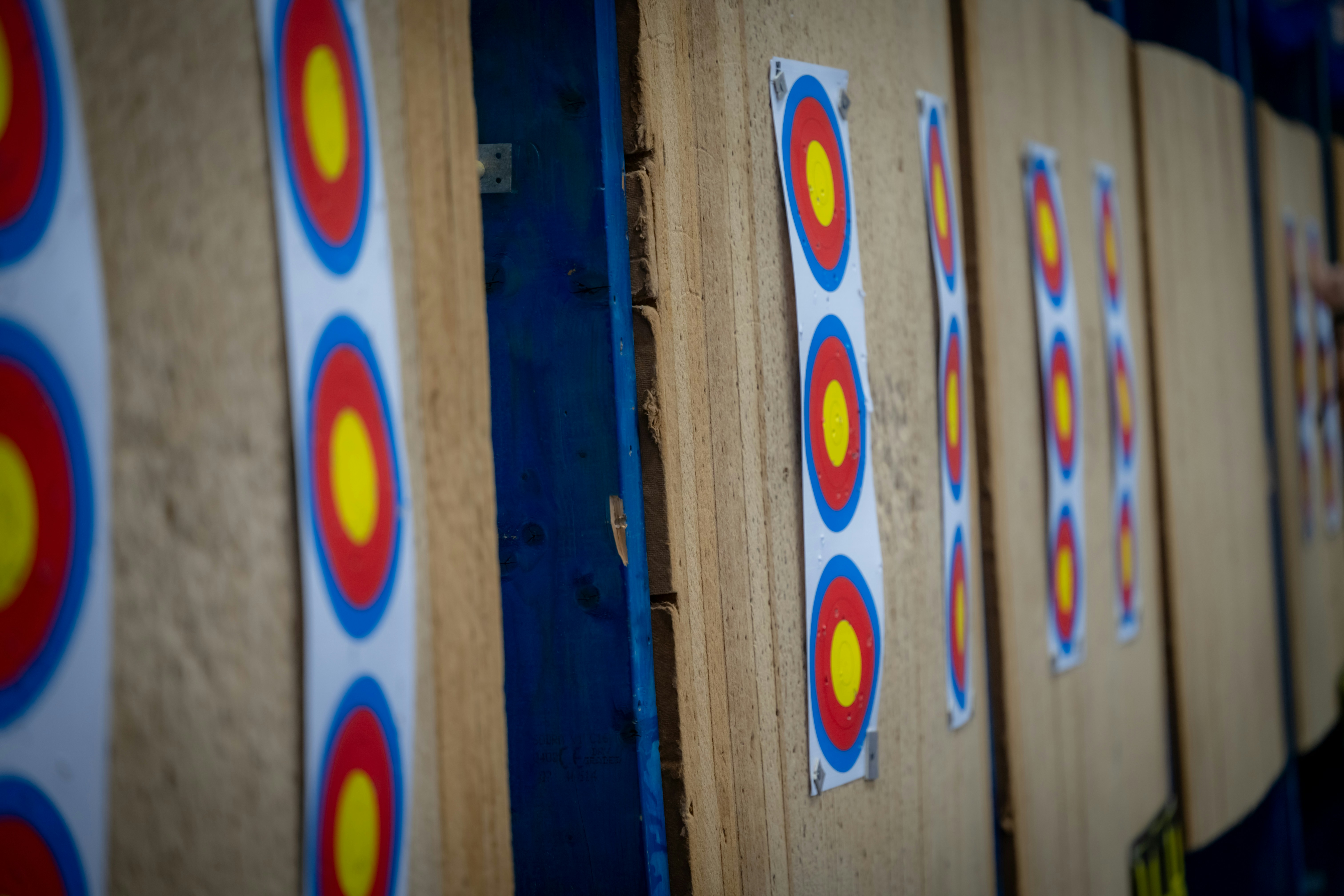 Archery targets lined up on a wooden wall at an outdoor range