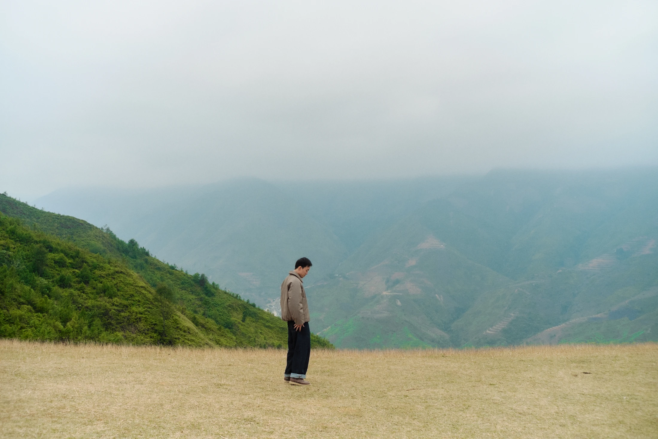 Lone person standing in a quiet, misty mountain landscape