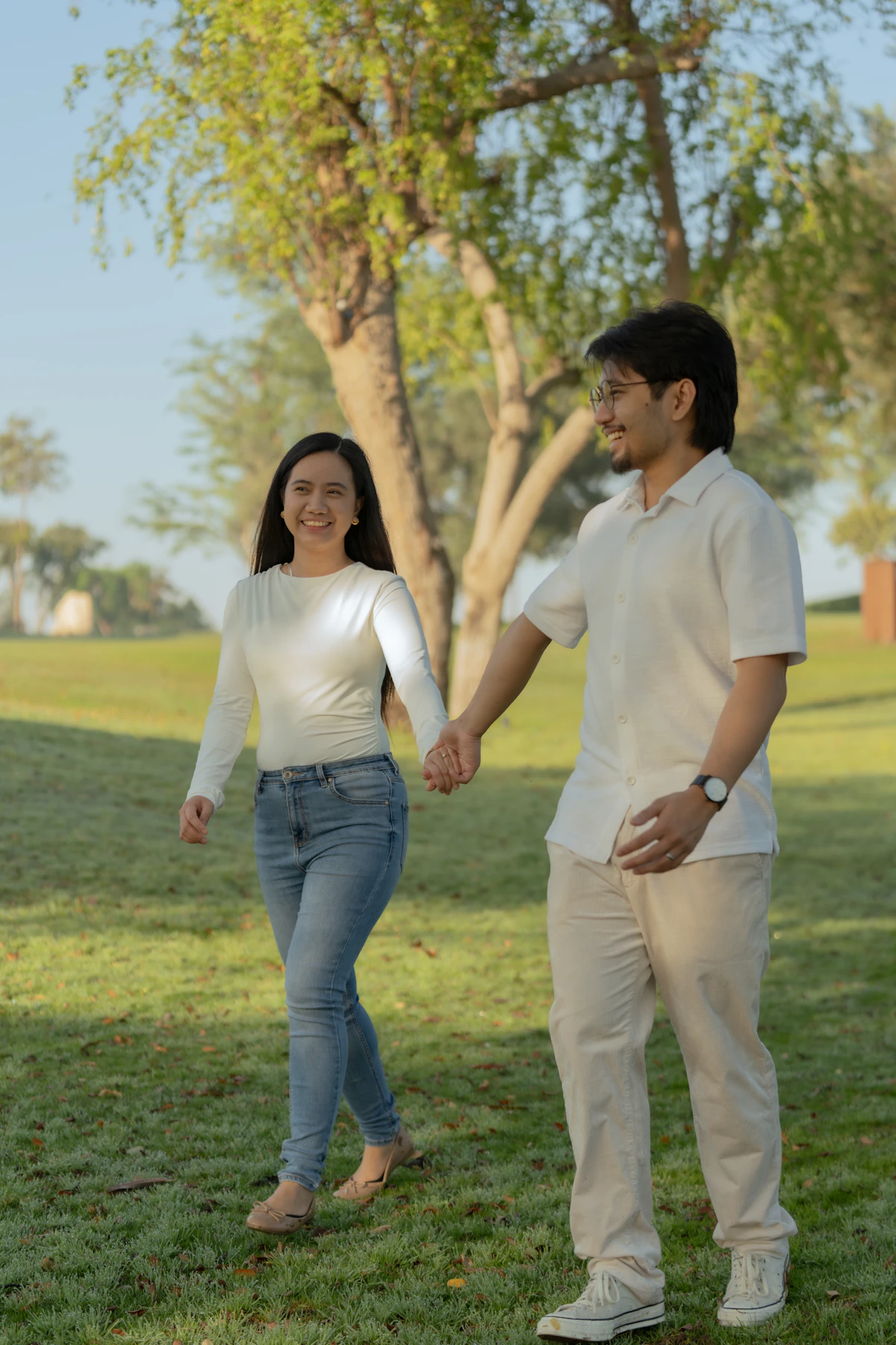 Paar geht gemeinsam Hand in Hand durch einen grünen Park
