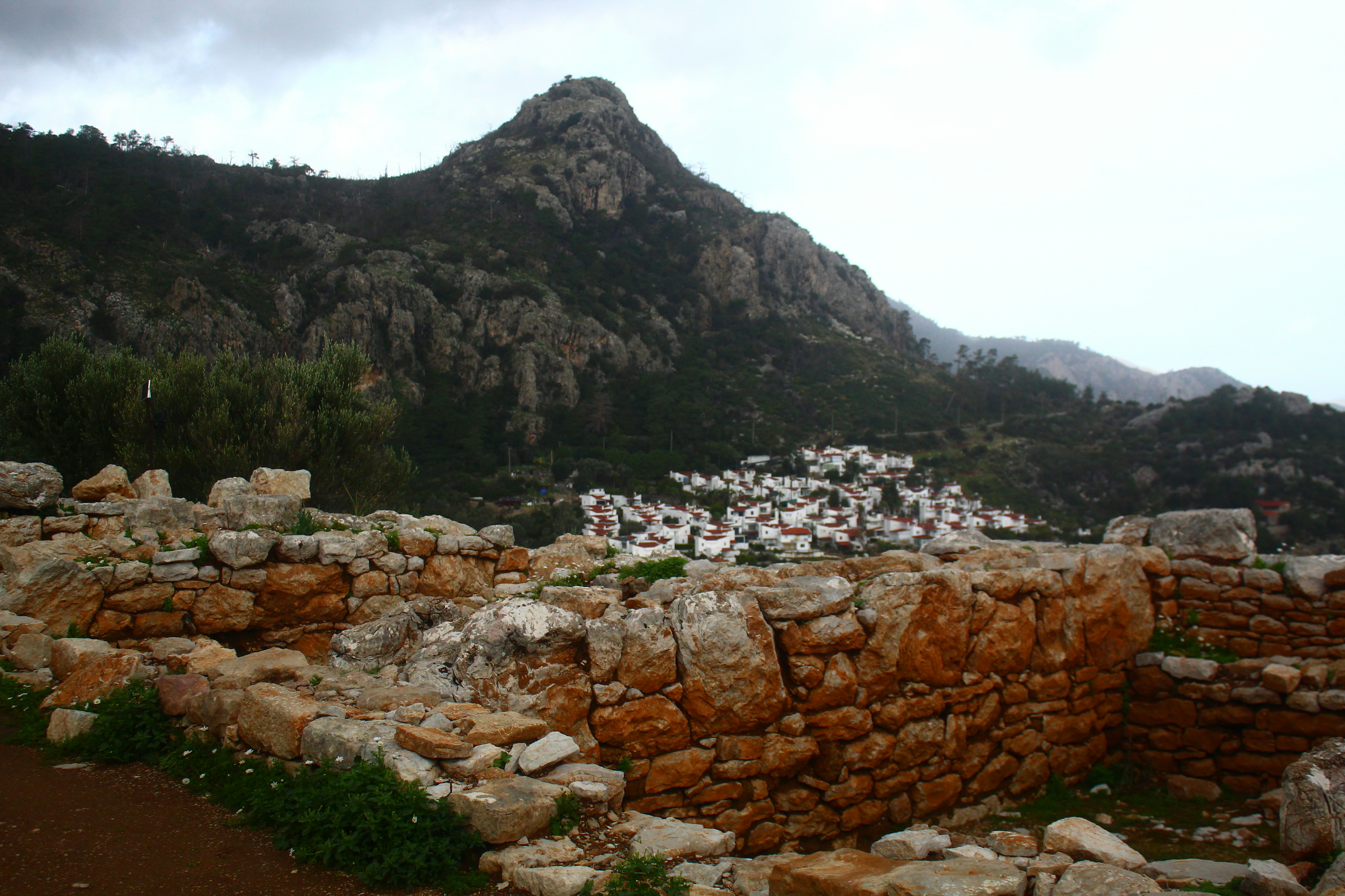 Ancient ruins with a village nestled below a mountain.