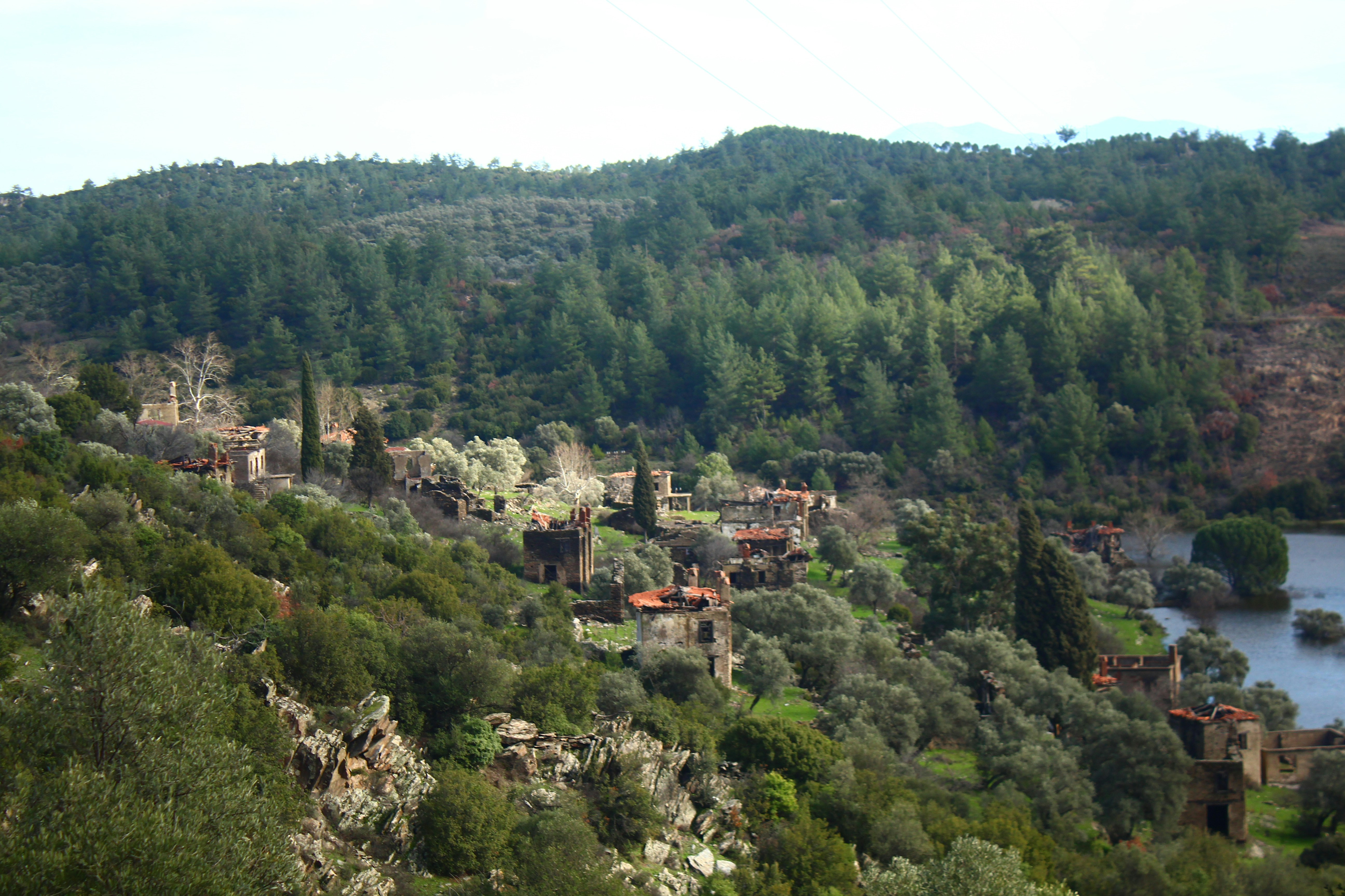 Ruined village nestled in a green, forested hillside.