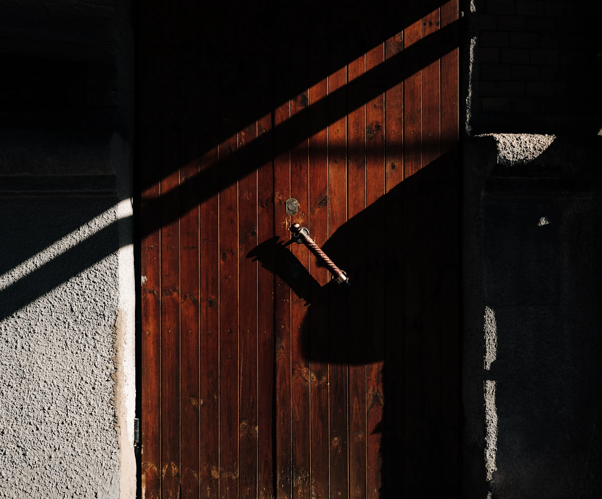 Pintu kayu dengan gagang logam dan bayangan tajam