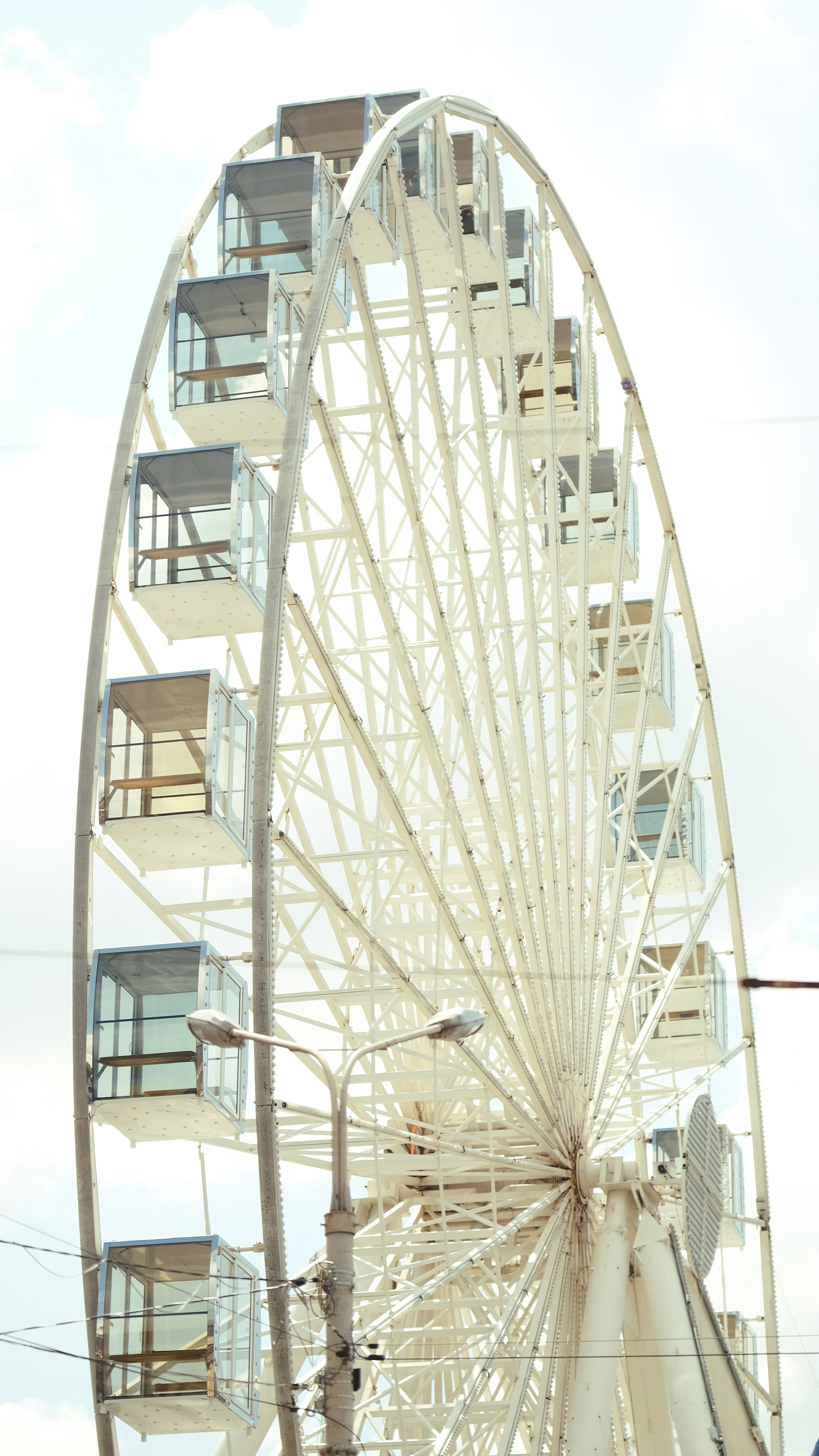 A white ferris wheel against a cloudy sky