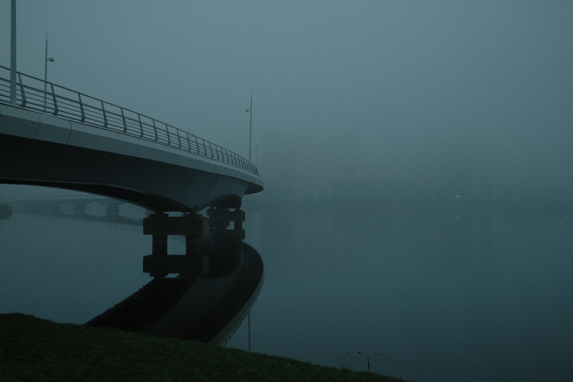 Modern bridge extending into fog above still water