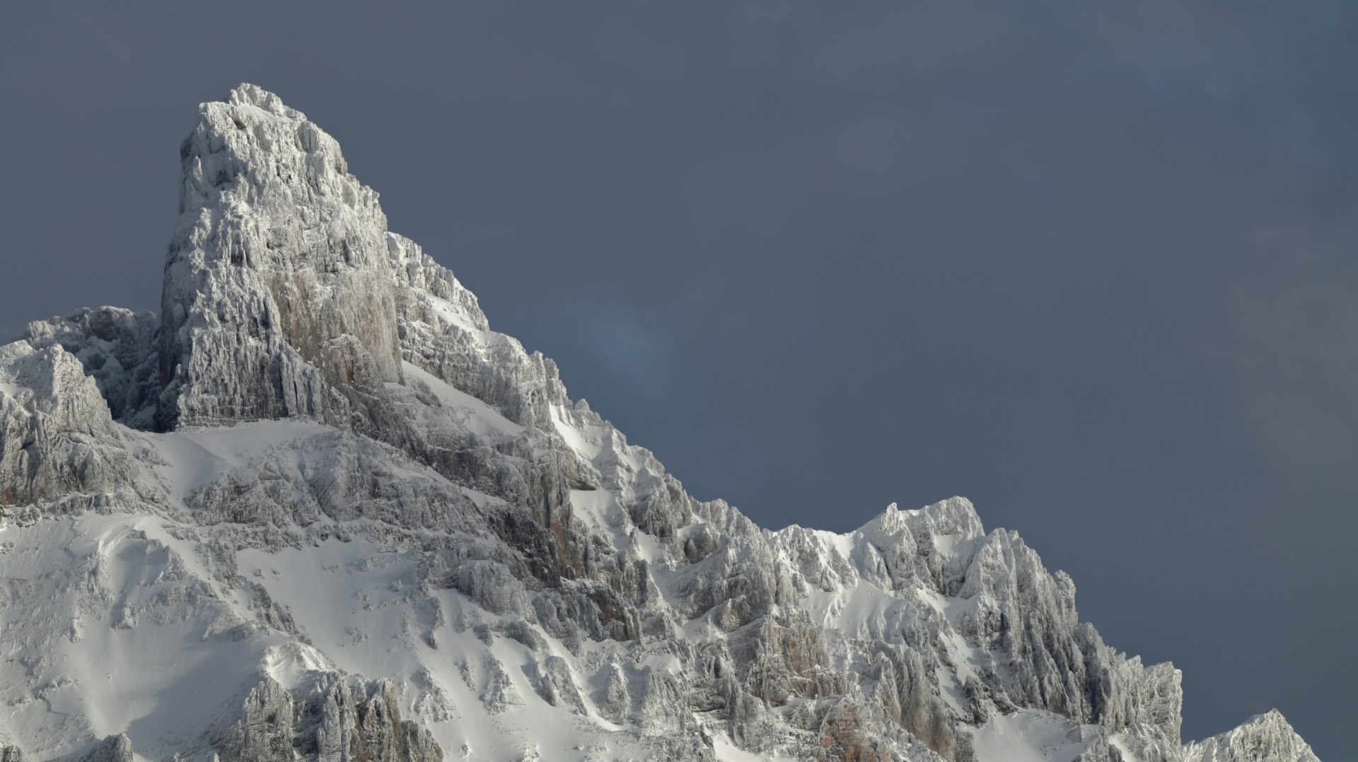 Snow-covered jagged mountain peak against dark sky