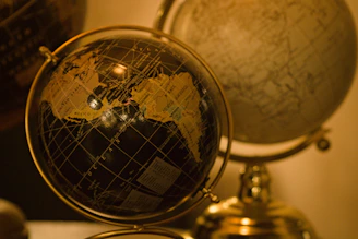 Two antique globes displayed on a shelf.