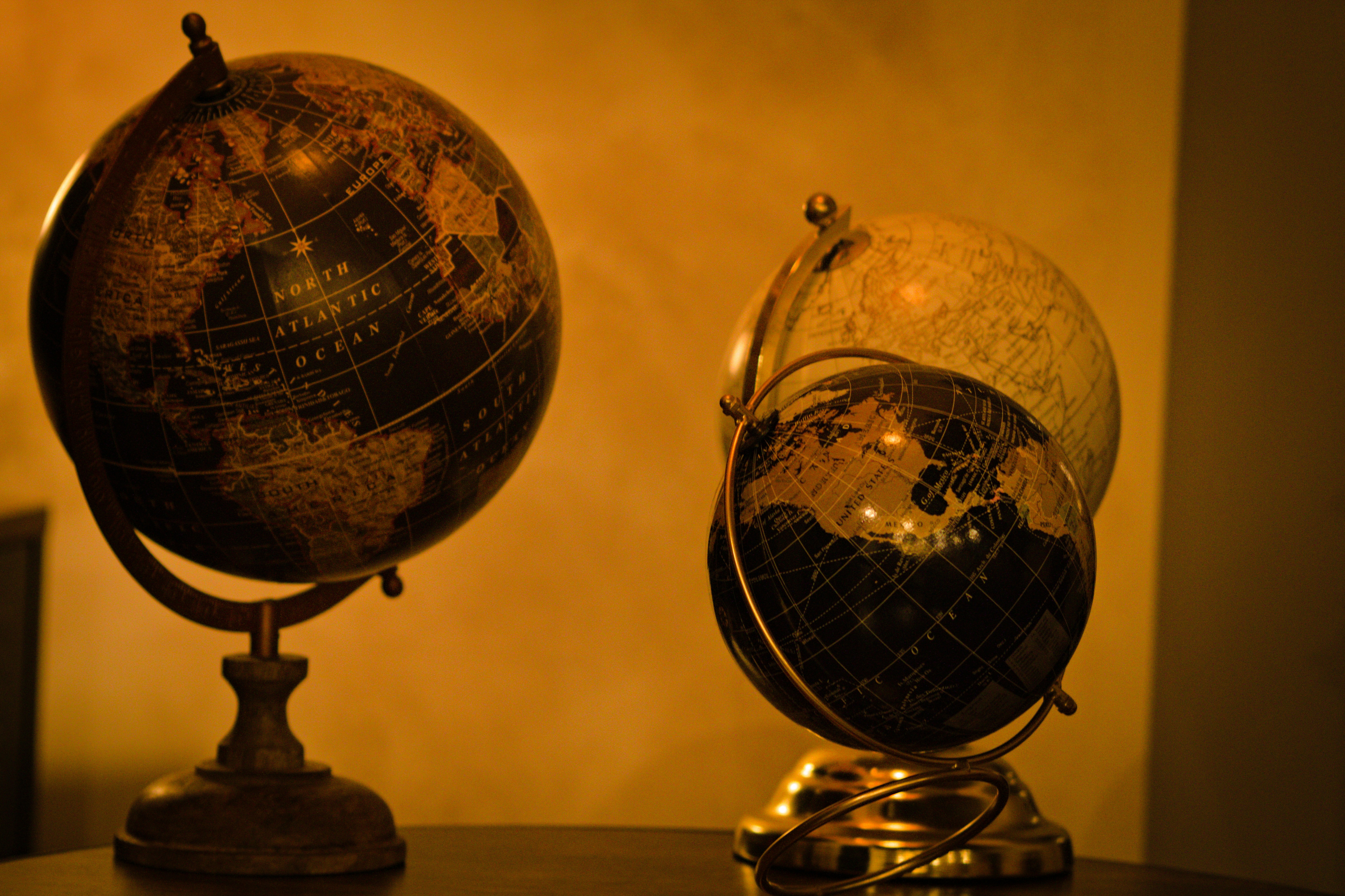 Three antique globes on a wooden surface