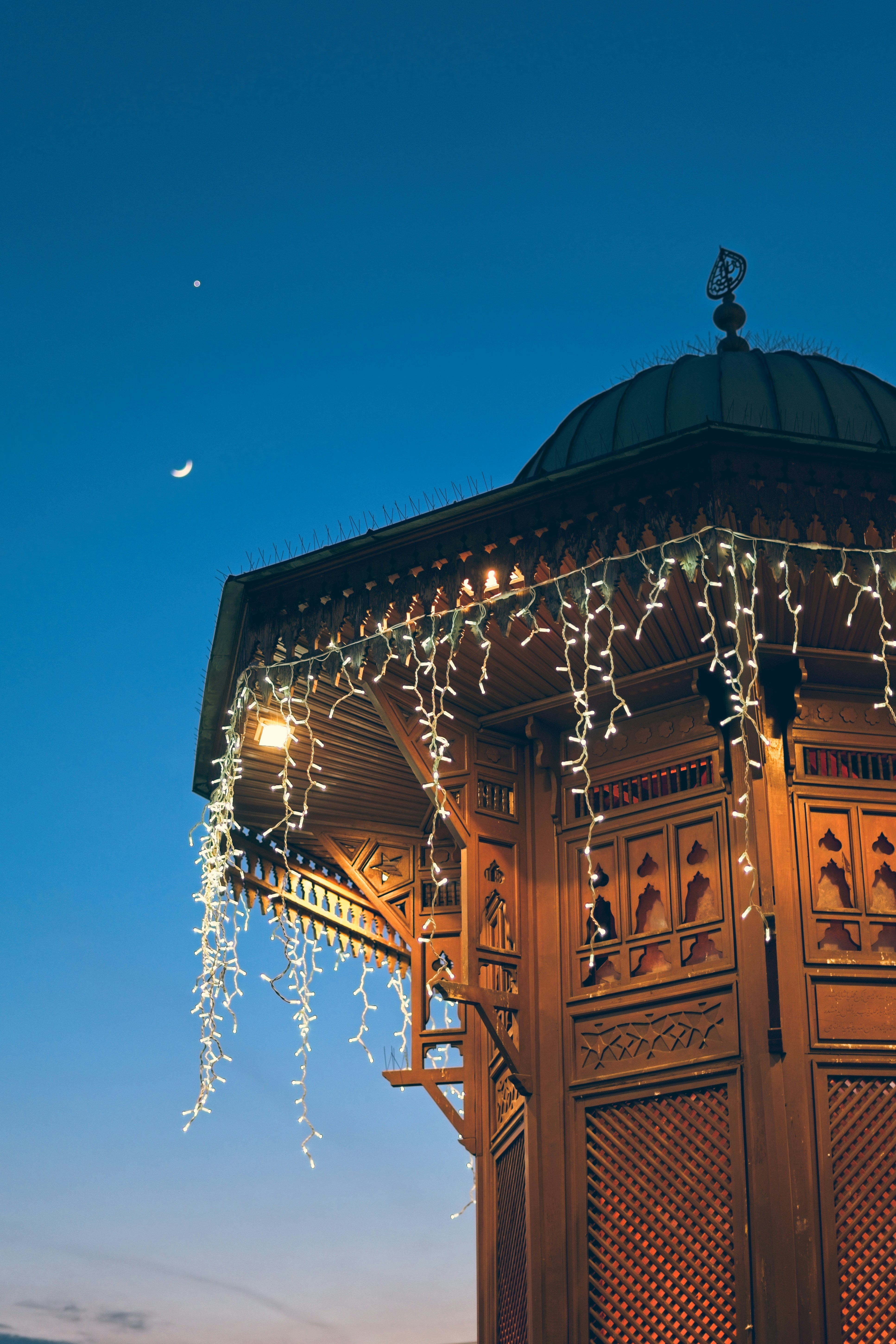 Estructura ornamentada de madera con luces festivas bajo el cielo crepuscular