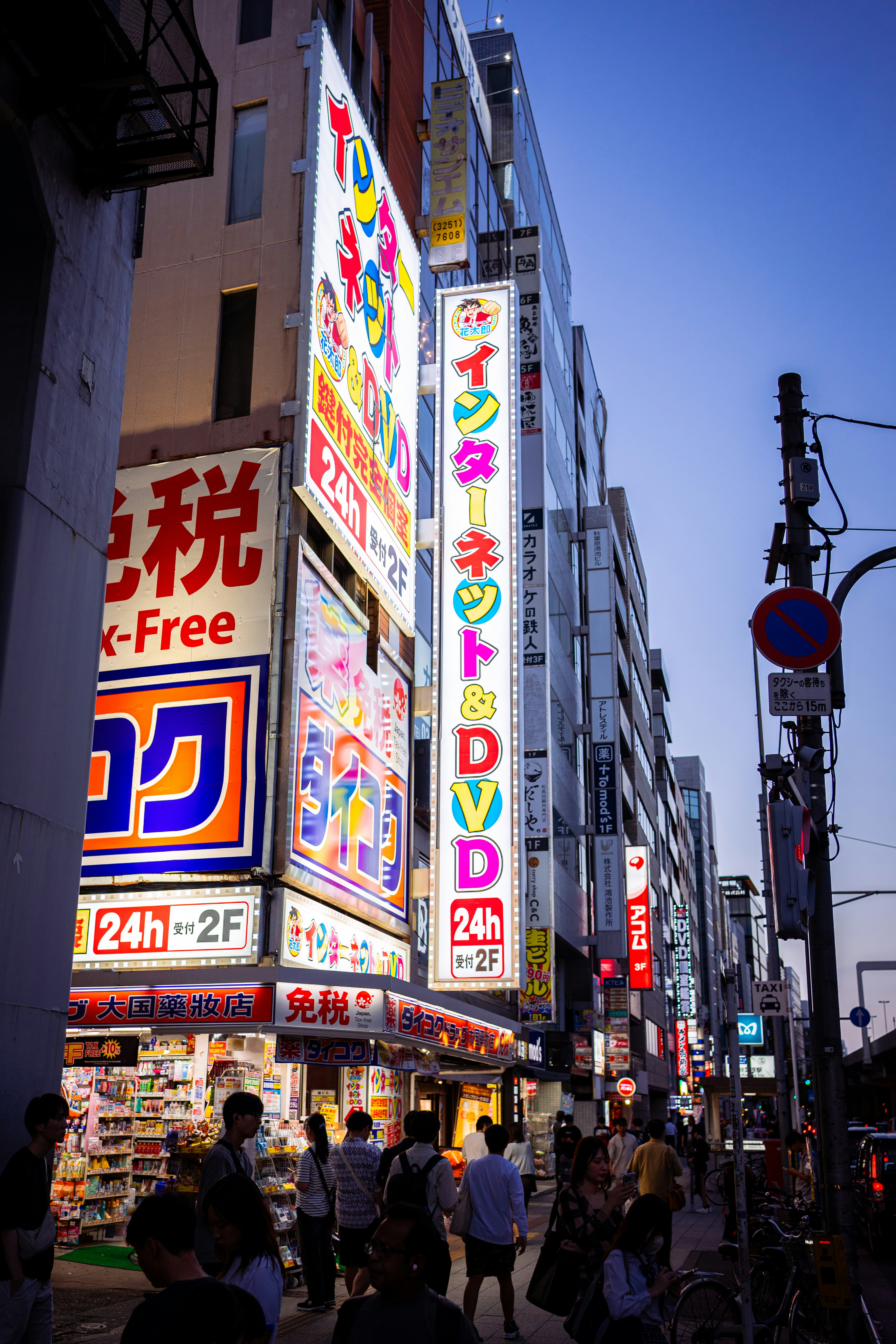 Brightly lit street with shops and signs at dusk