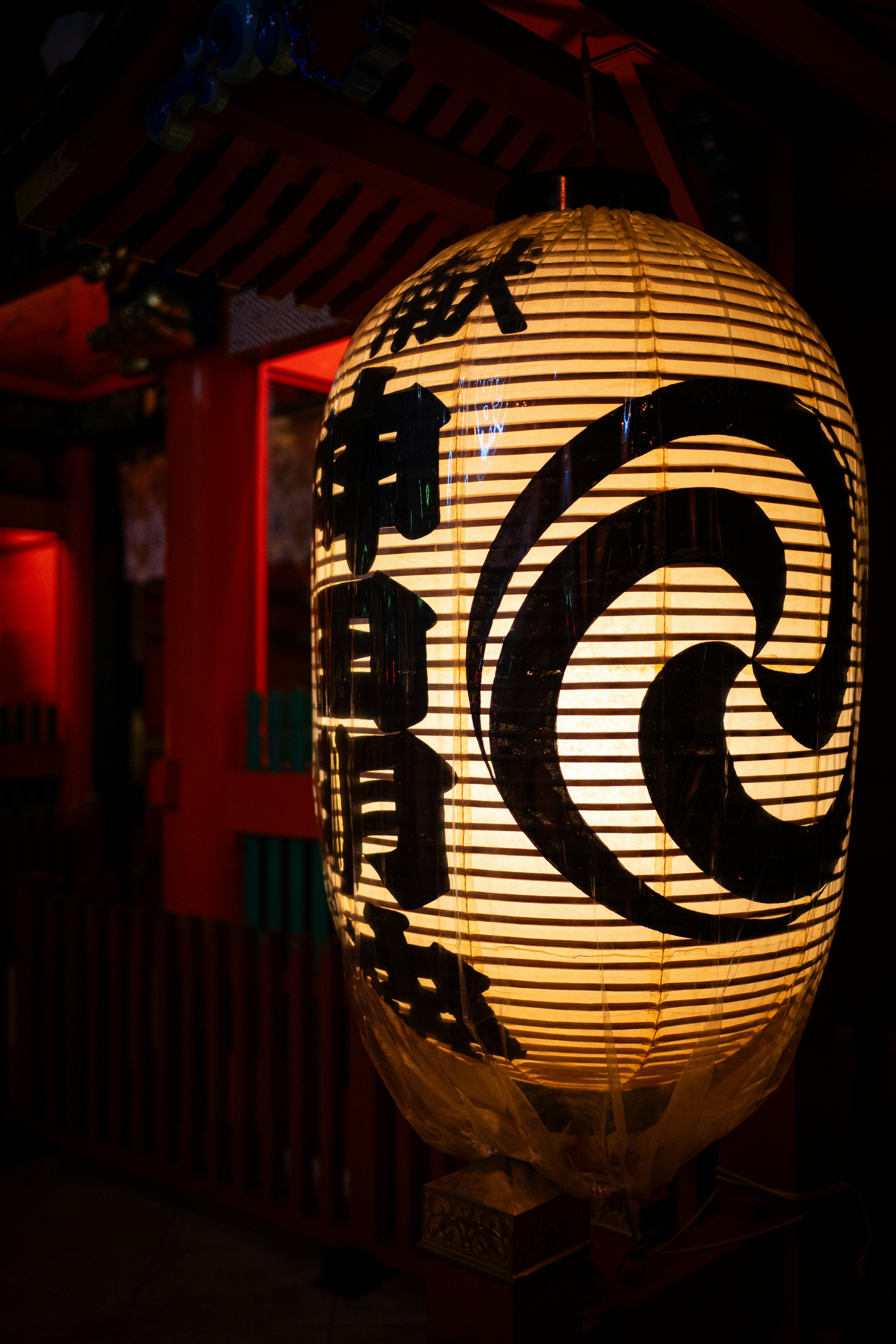 A traditional japanese lantern with black calligraphy and spiral design.