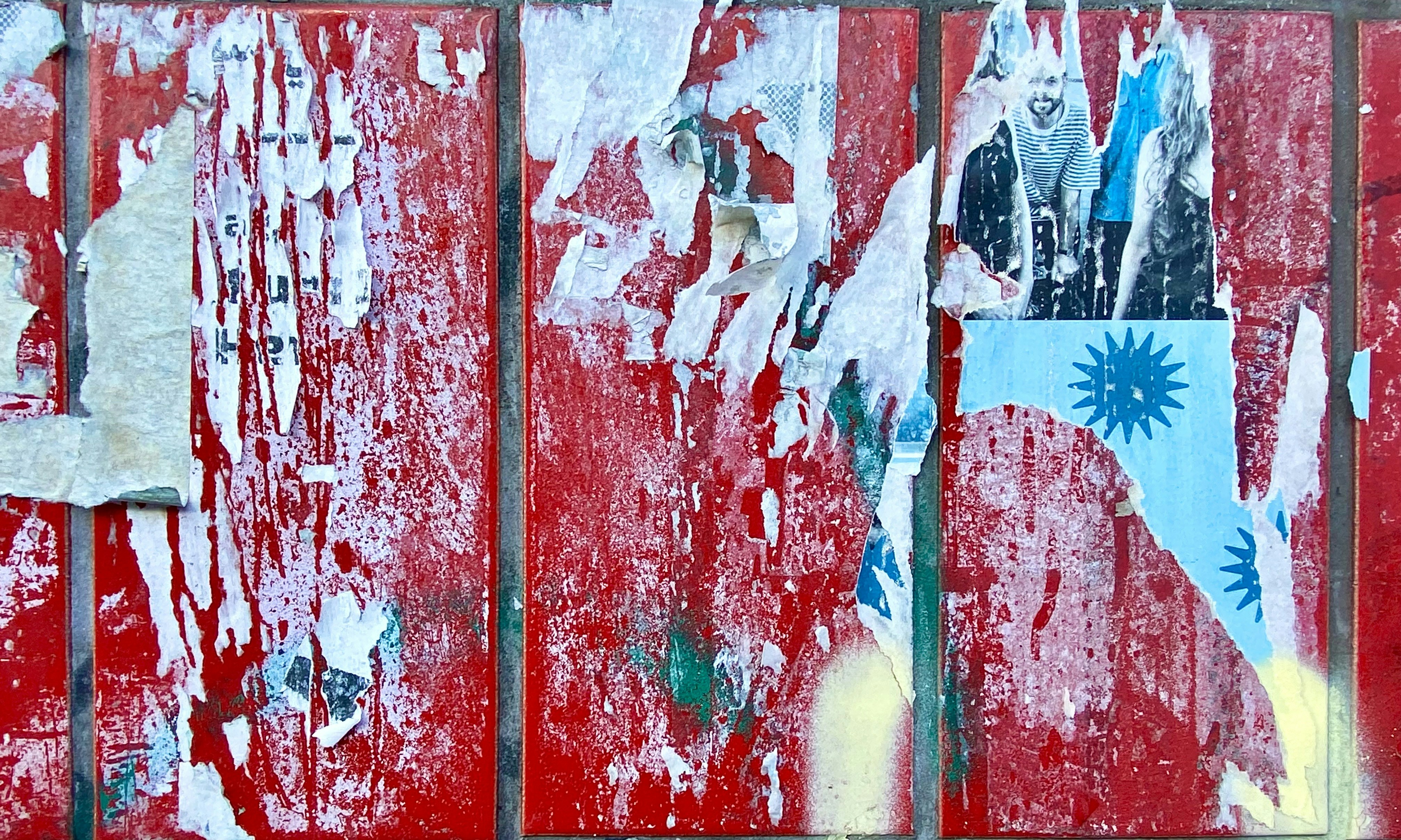 Torn posters on a weathered red wall