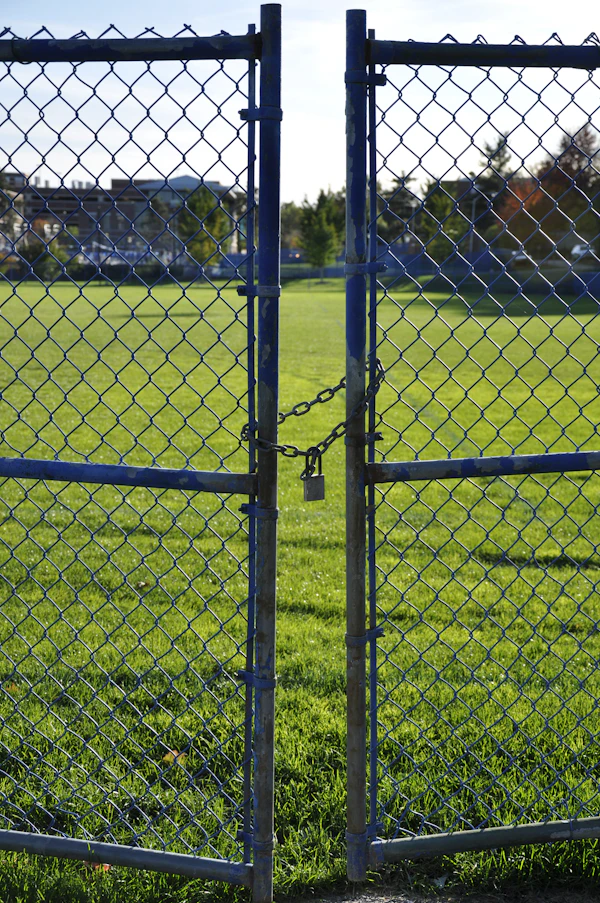 Chain link fence with a locked double gate on a grassy field