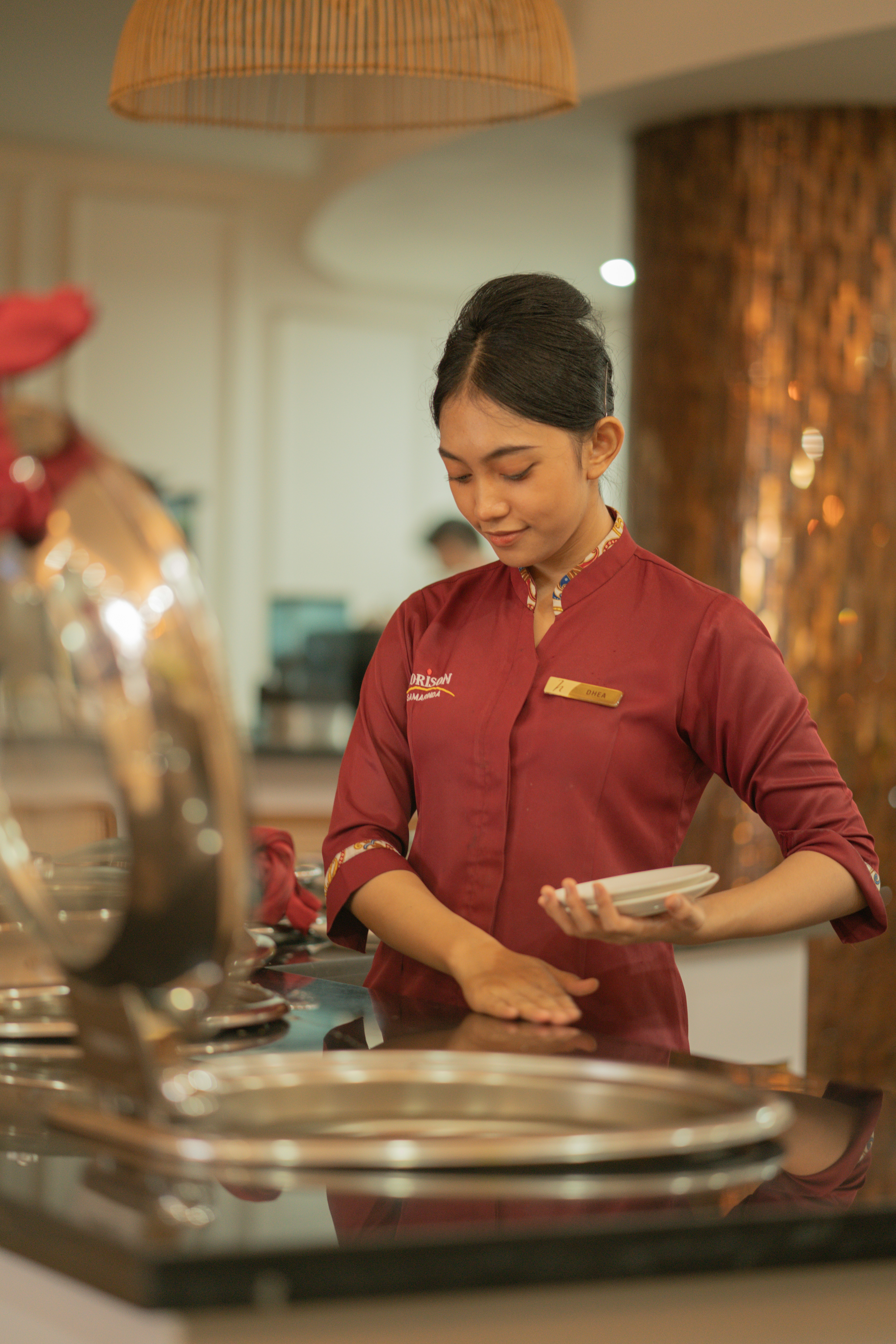 A server in a maroon uniform arranging plates