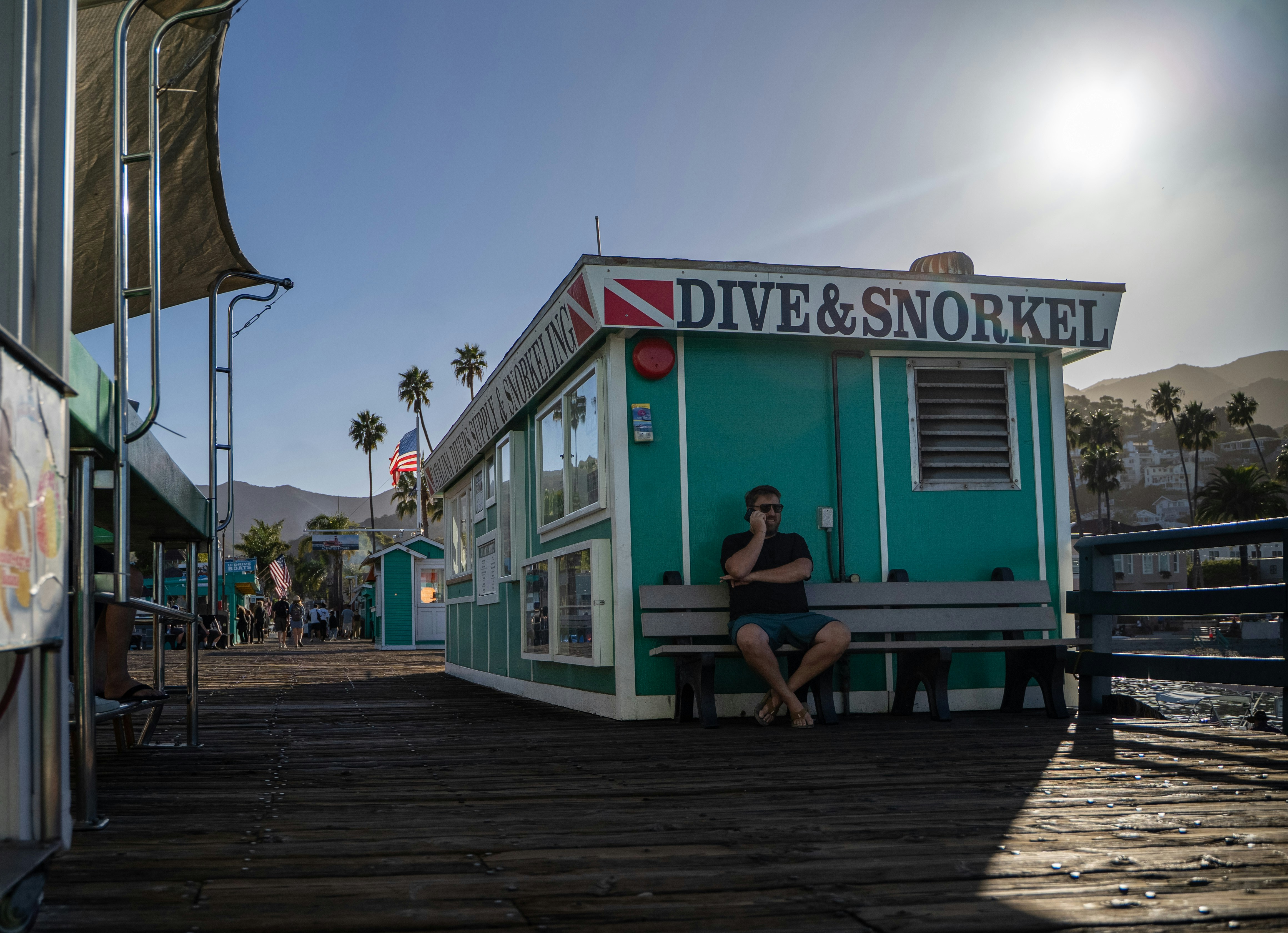 남자가 청록색 다이빙 및 스노클링 샵 밖에 앉아 있다.