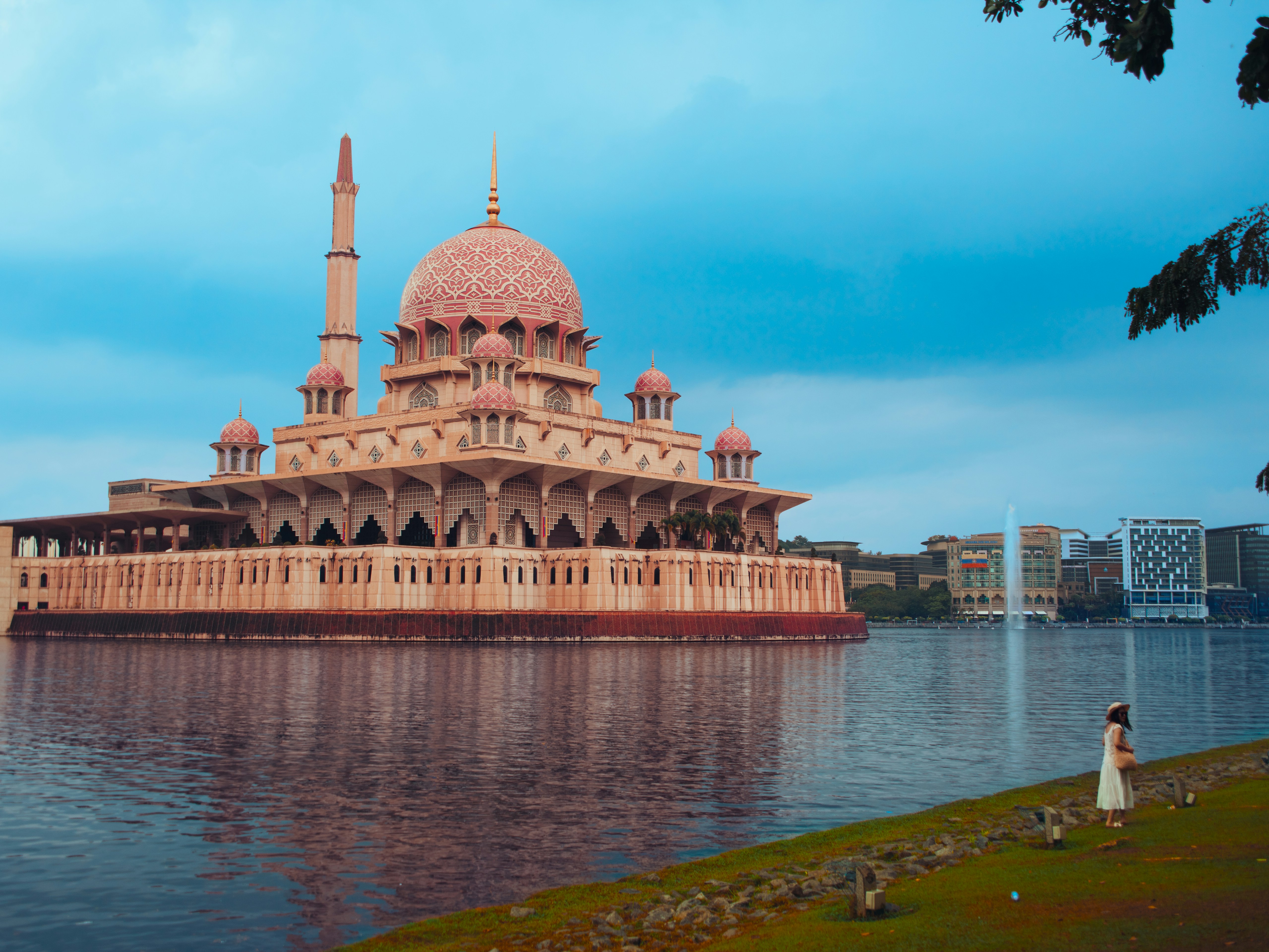 Pink mosque on a lake with a person watching