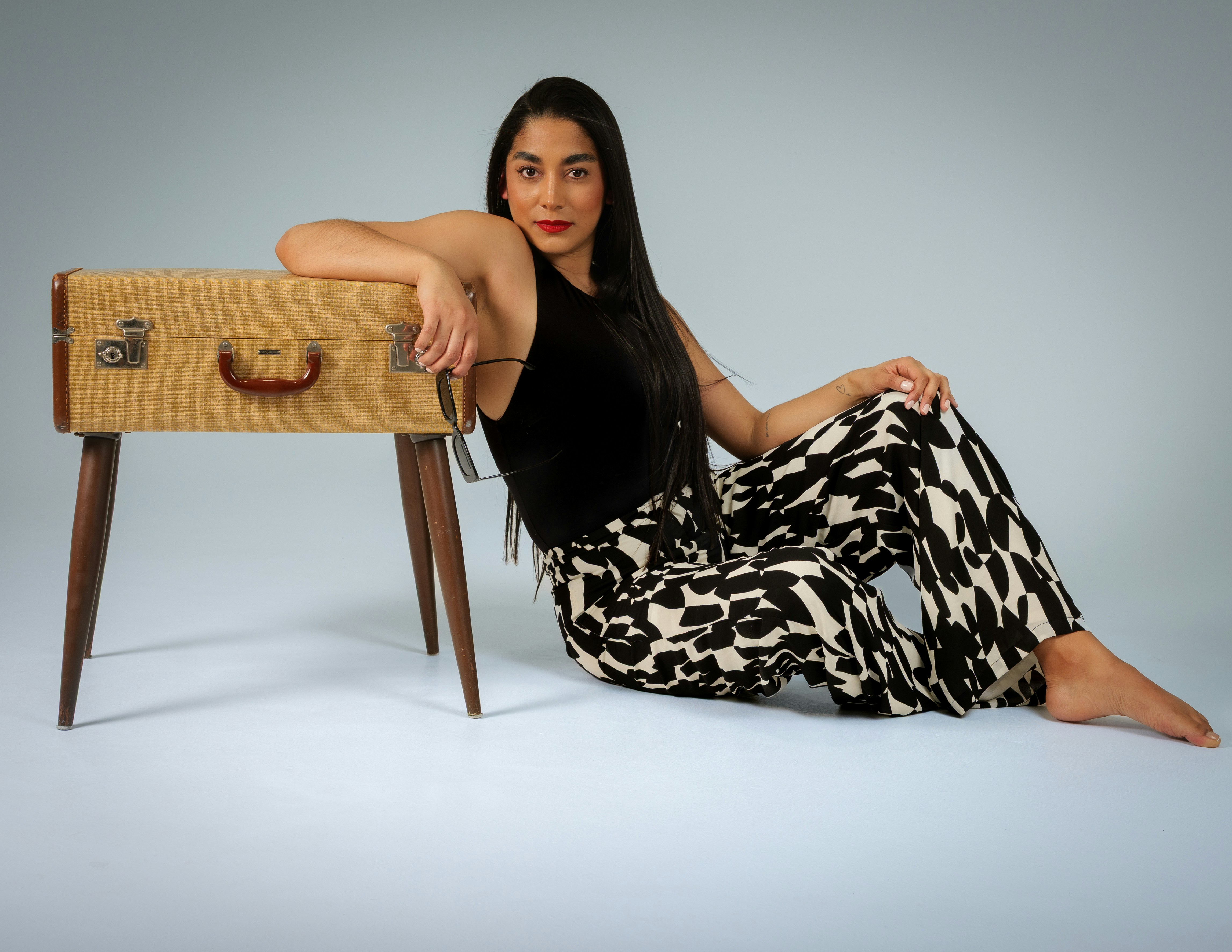 Frau sitzt neben einem Vintage-Koffer