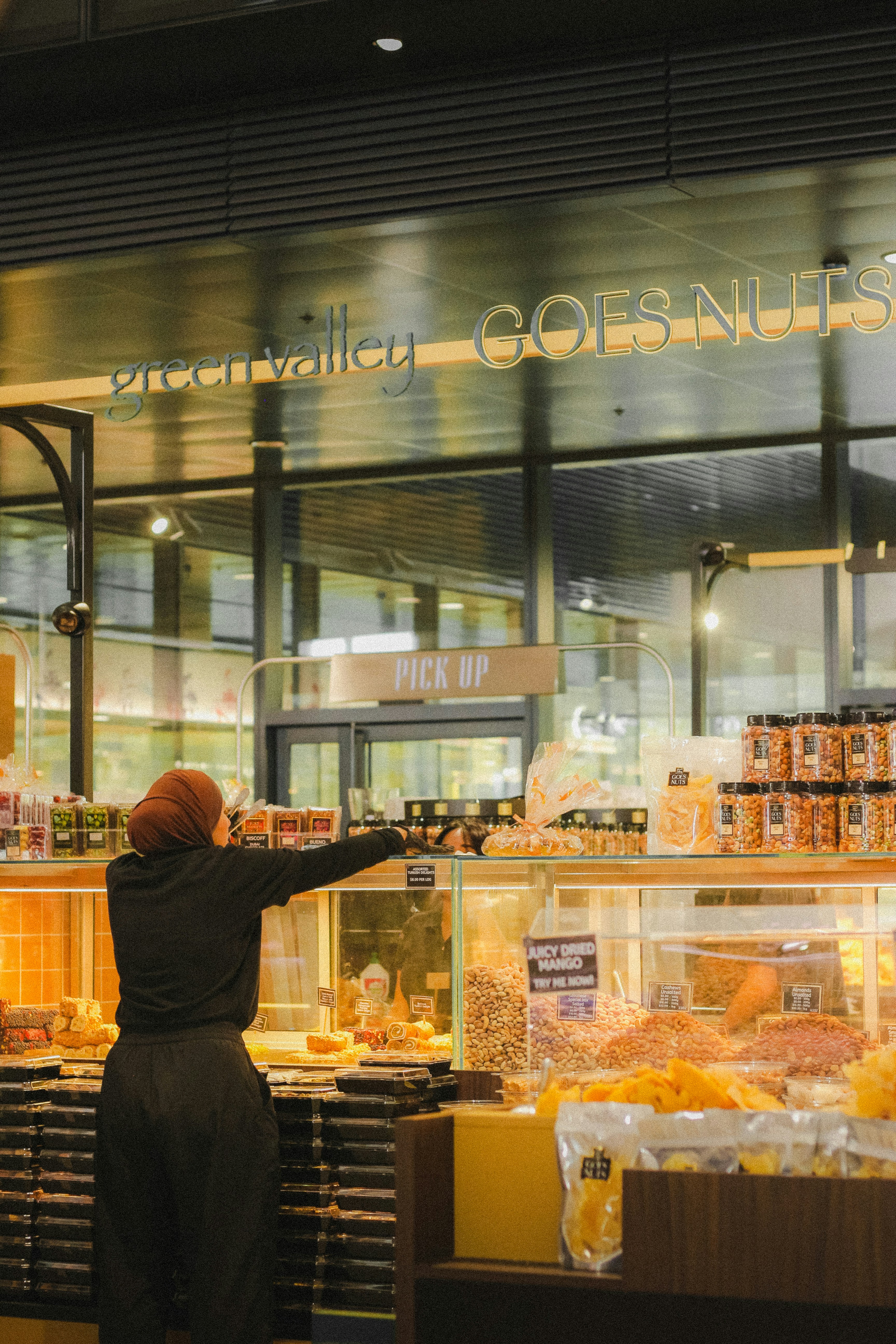 A person reaches for items in a well-stocked grocery store.