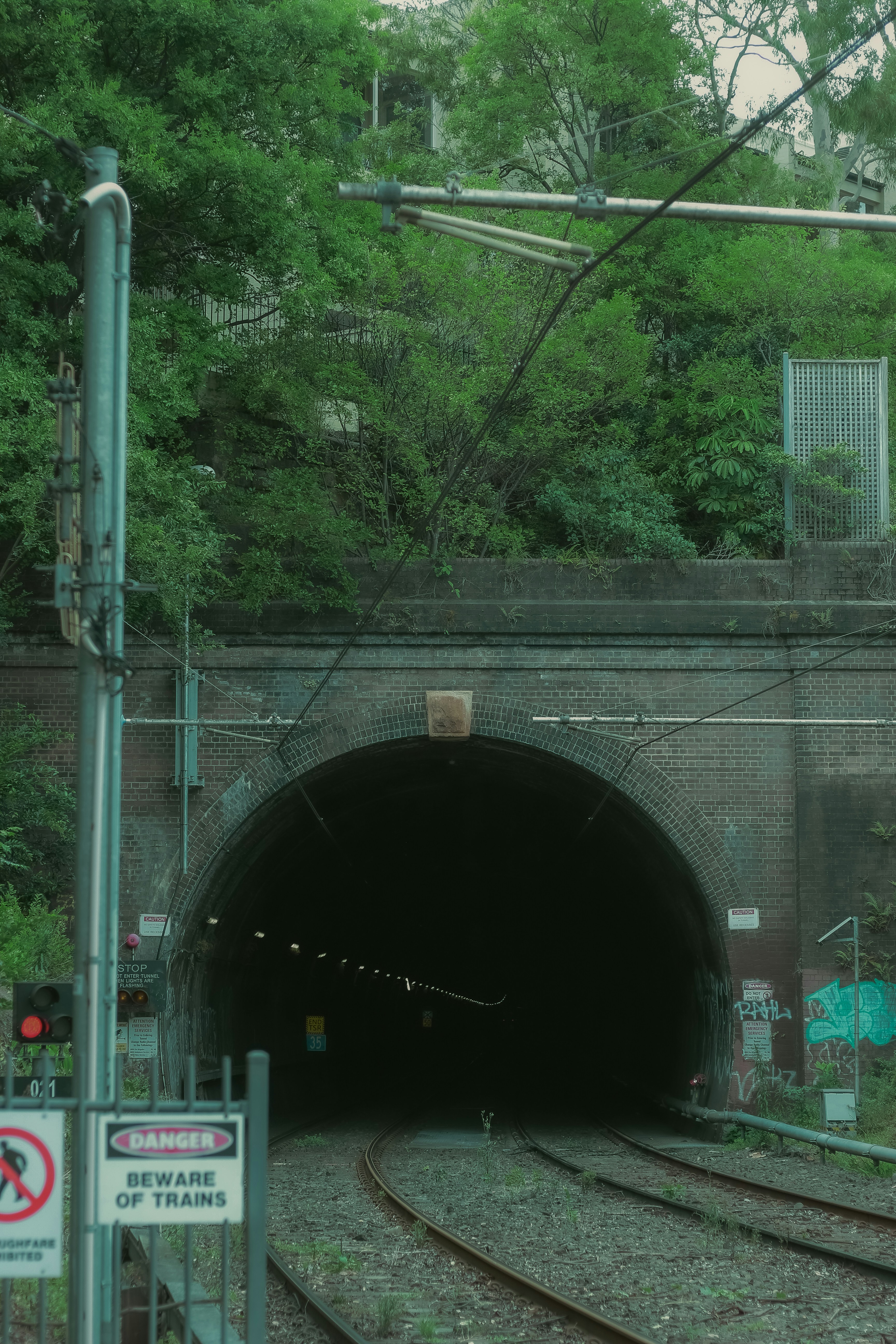 Train tunnel entrance with tracks and warning signs