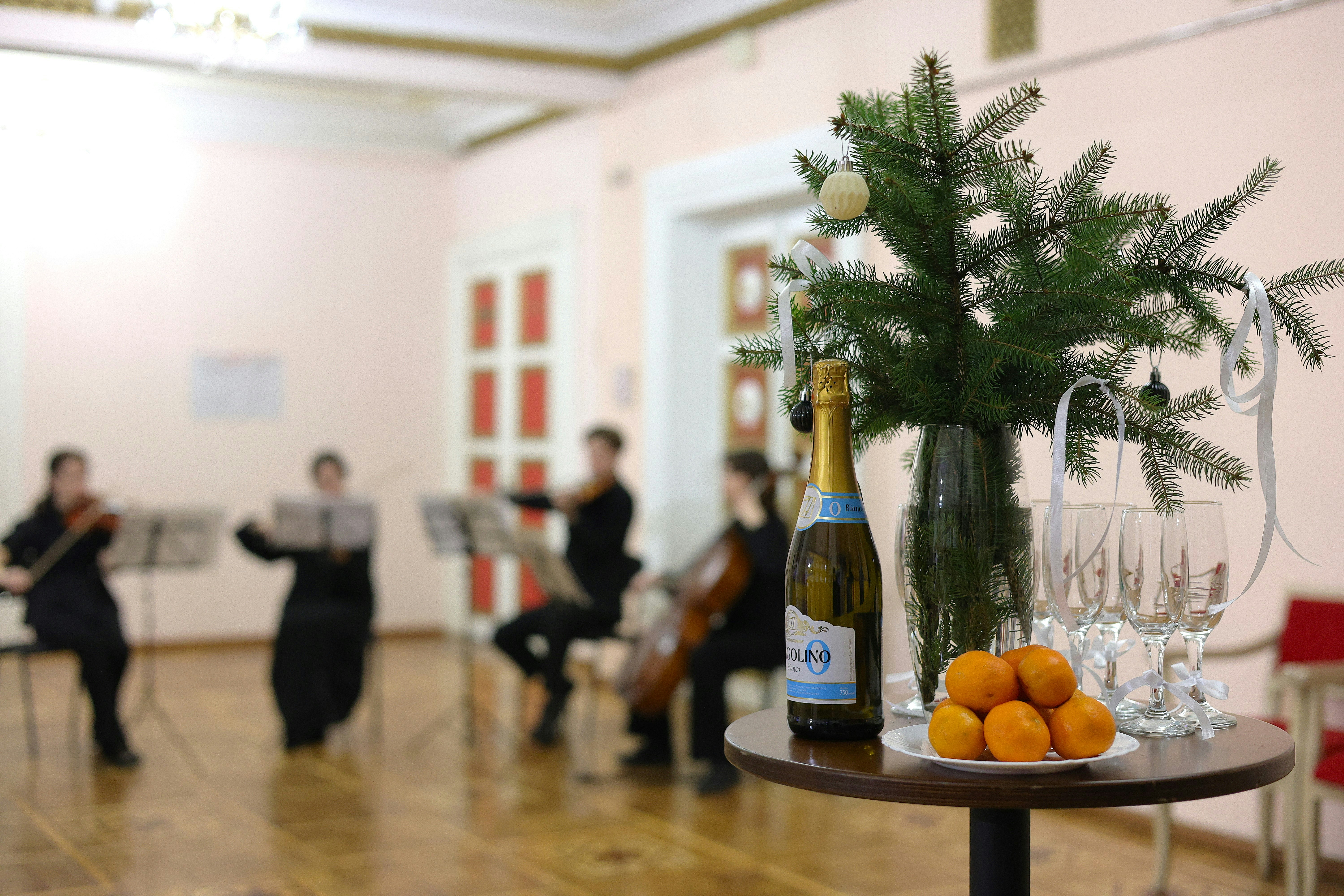 Musicians play near a decorated christmas tree and champagne.