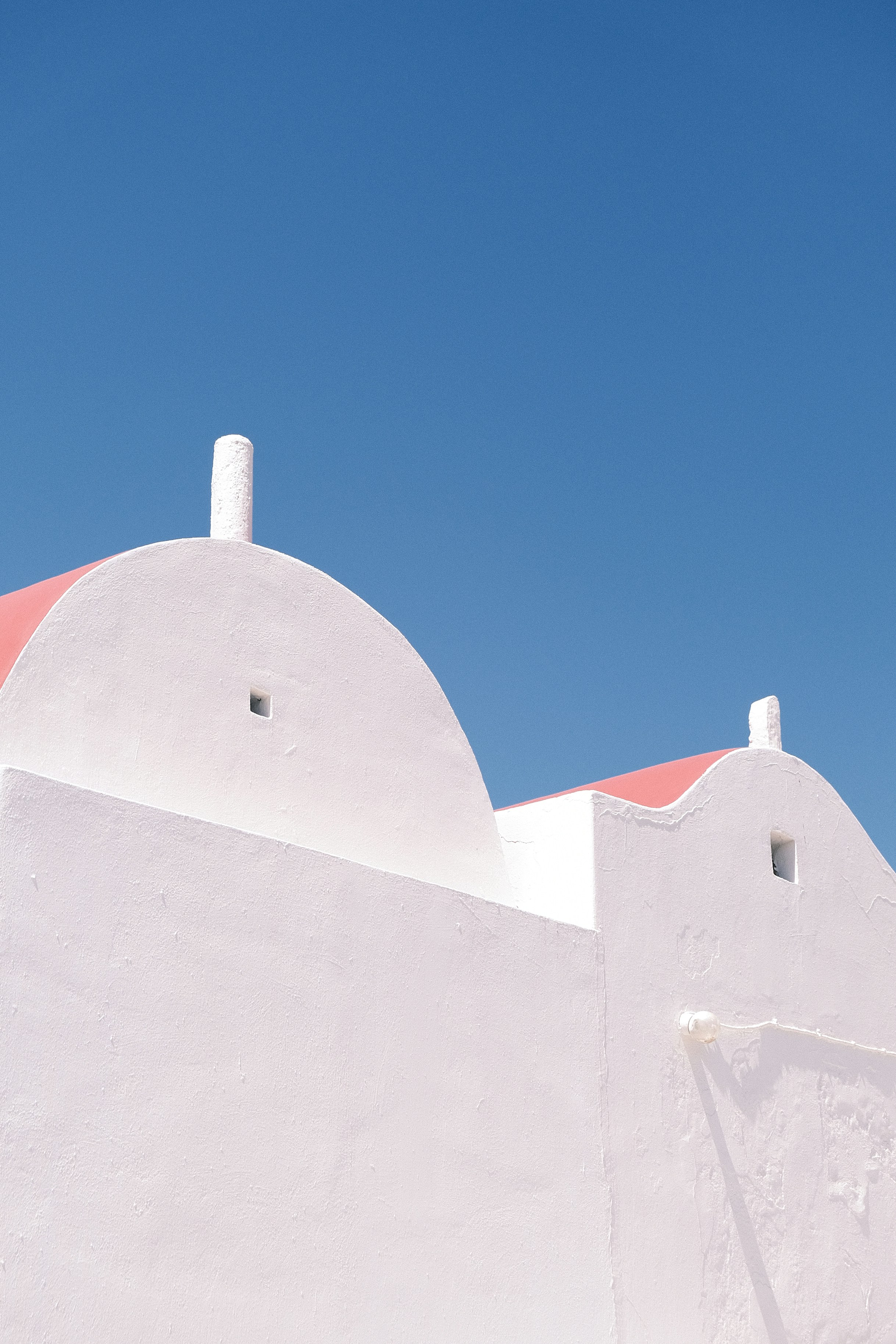 White buildings with pink roofs against blue sky