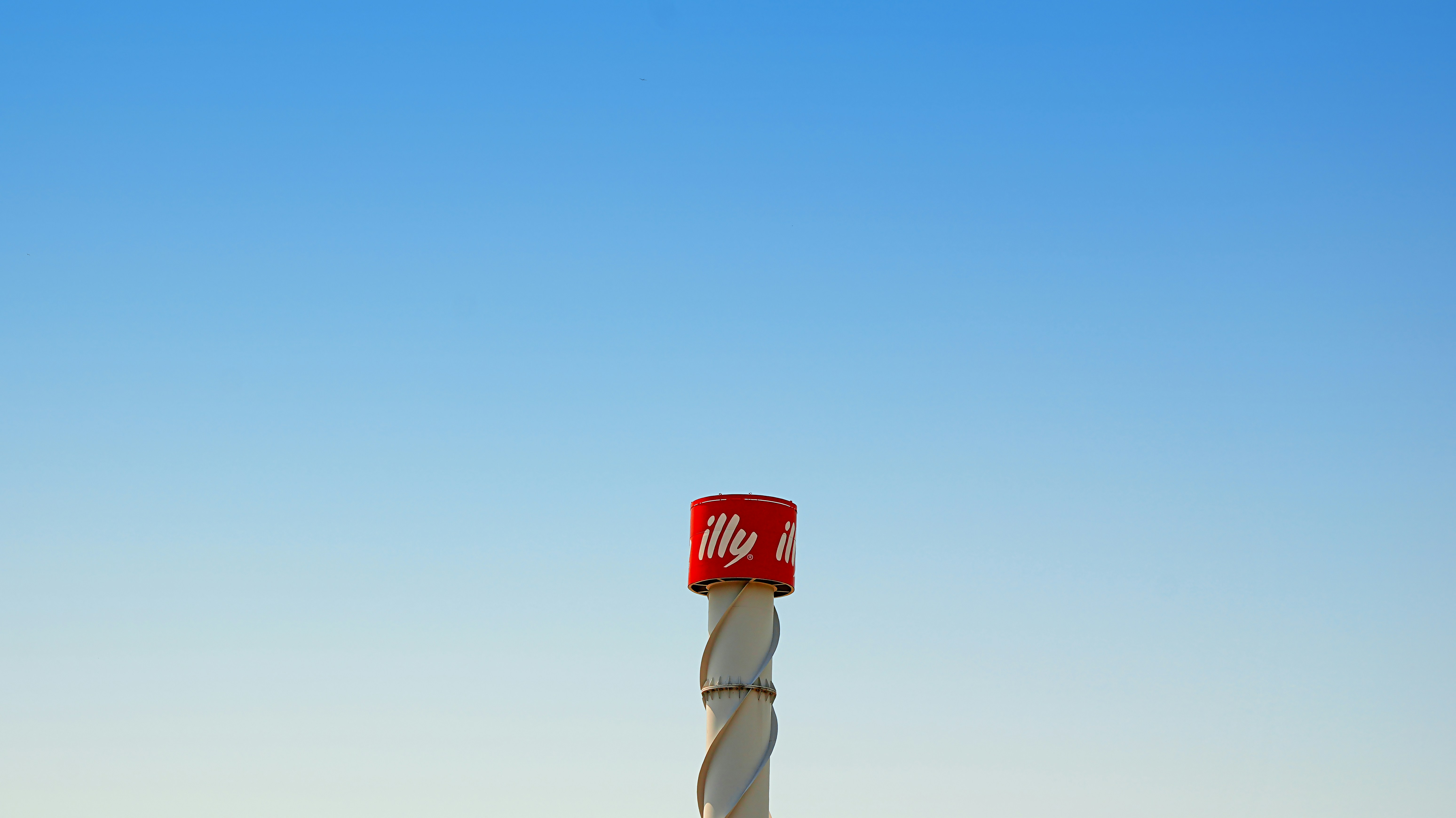 Canette de café illy rouge et blanche sur un poteau