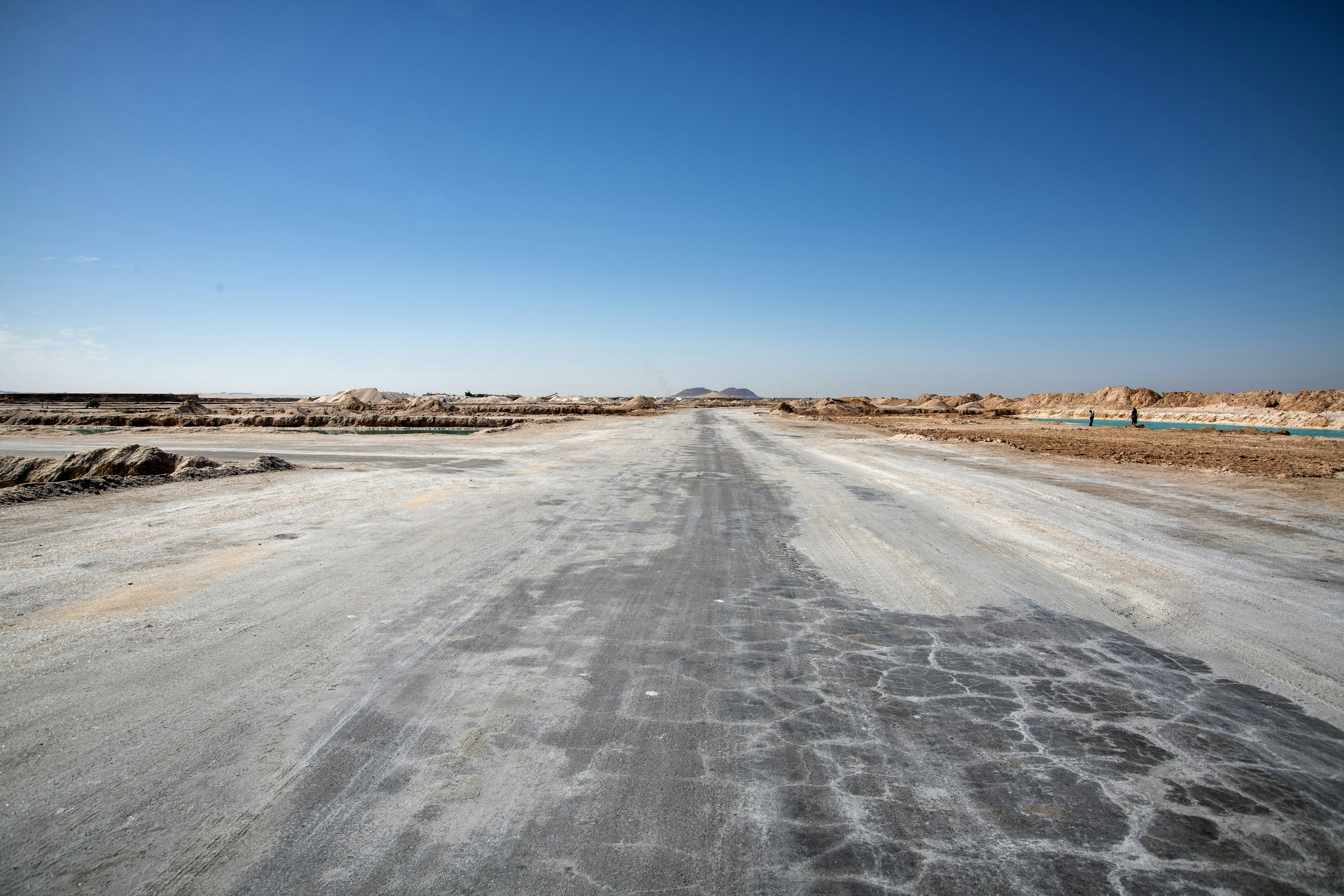 Cracked asphalt road leads to distant dry landscape