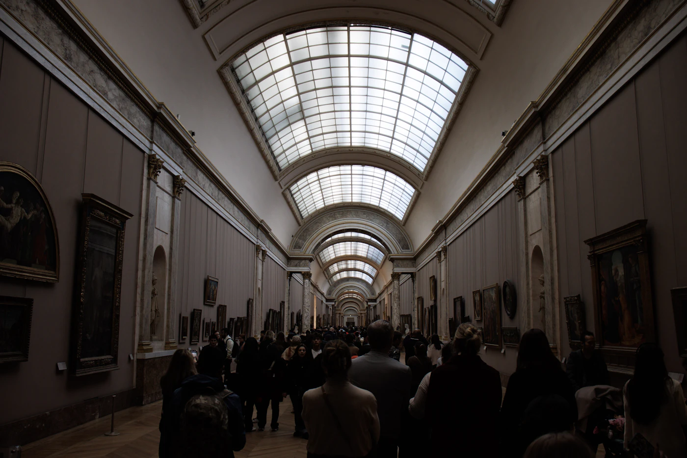 People walking through a long art gallery corridor