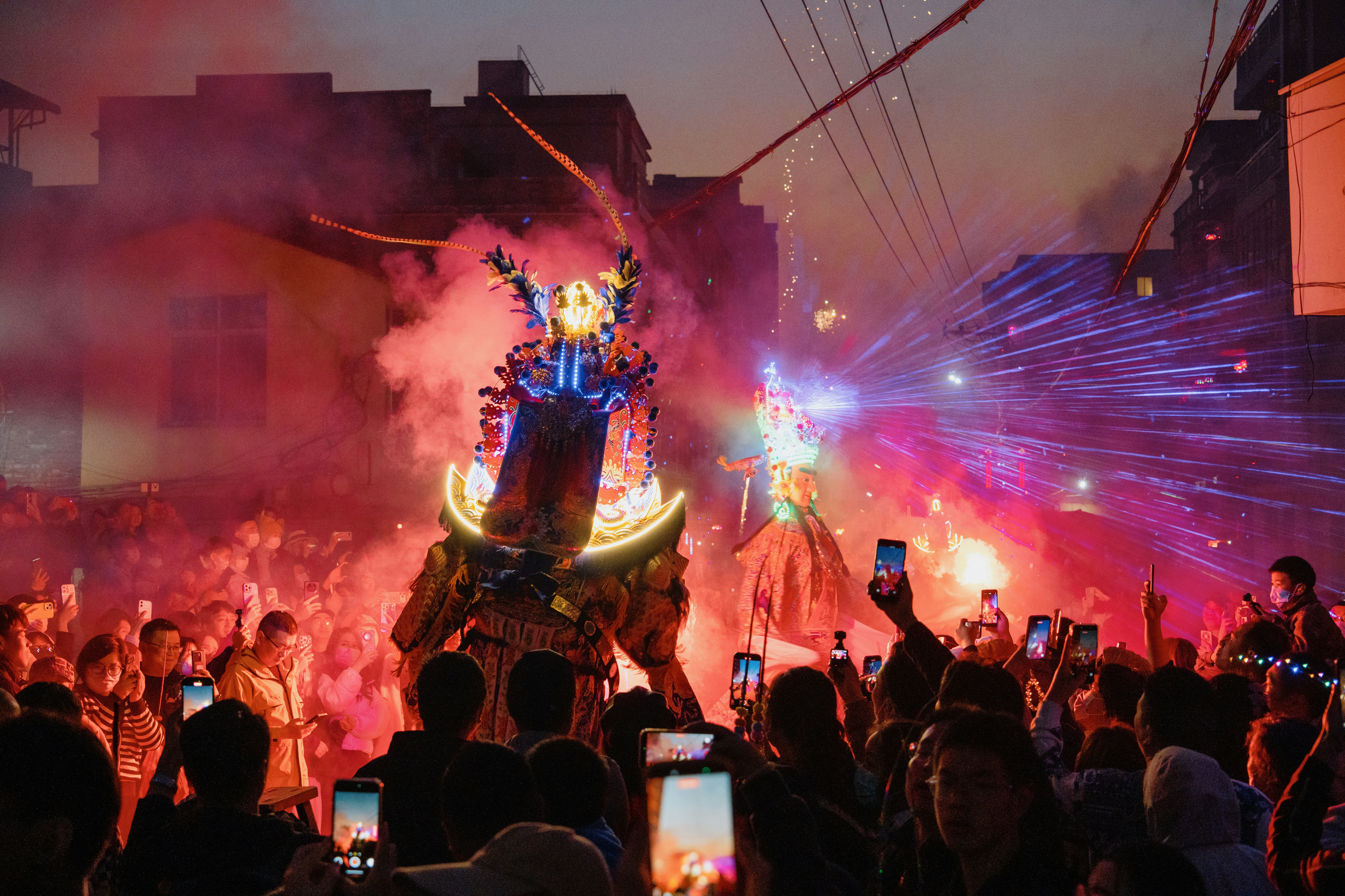 Les gens regardent une effigie lumineuse lors d’un festival avec des feux d’artifice.