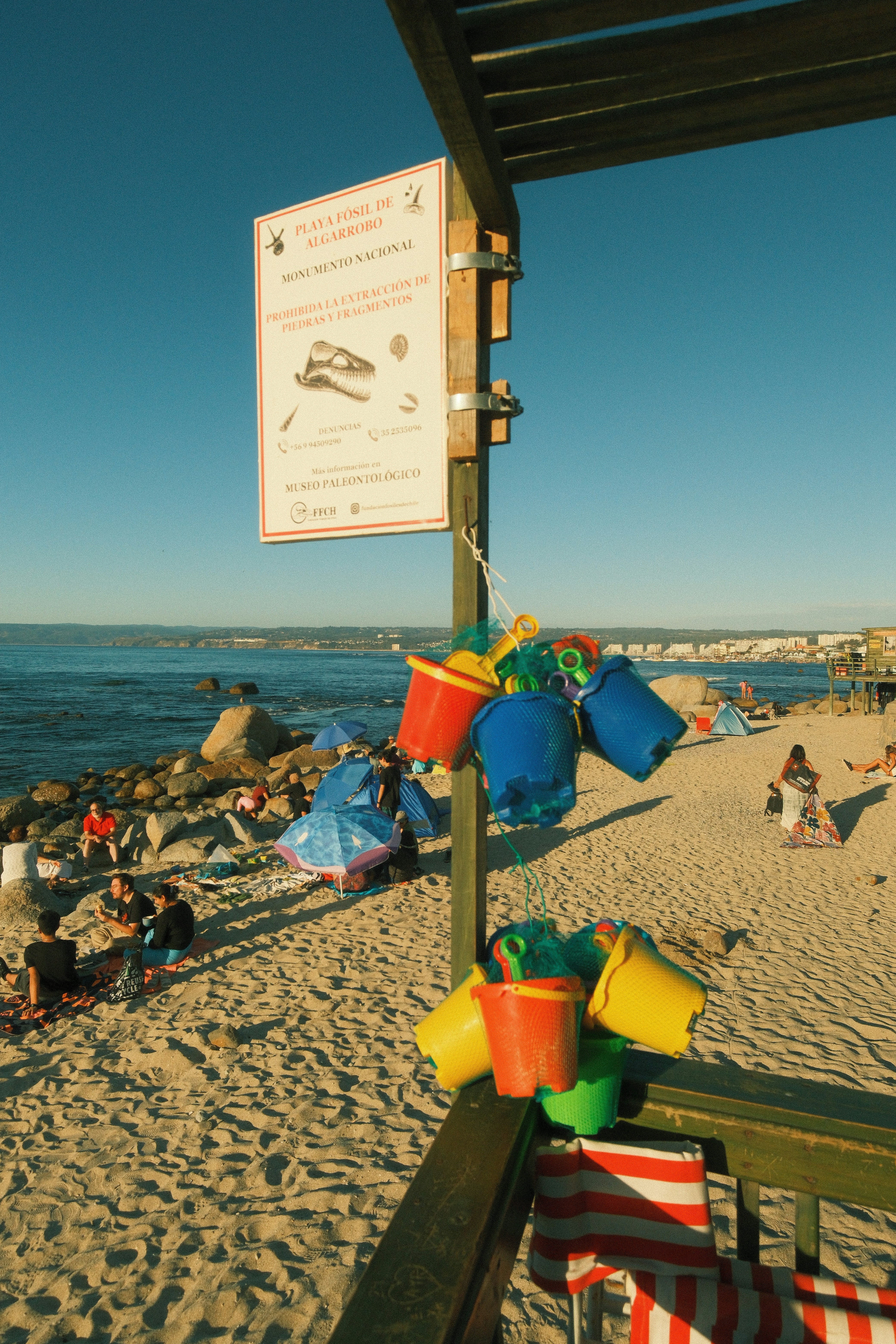 Bunte Eimer und Spaten hängen an einem Strandpfosten.