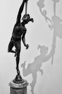 Bronze statue of a man with a torch and shadow