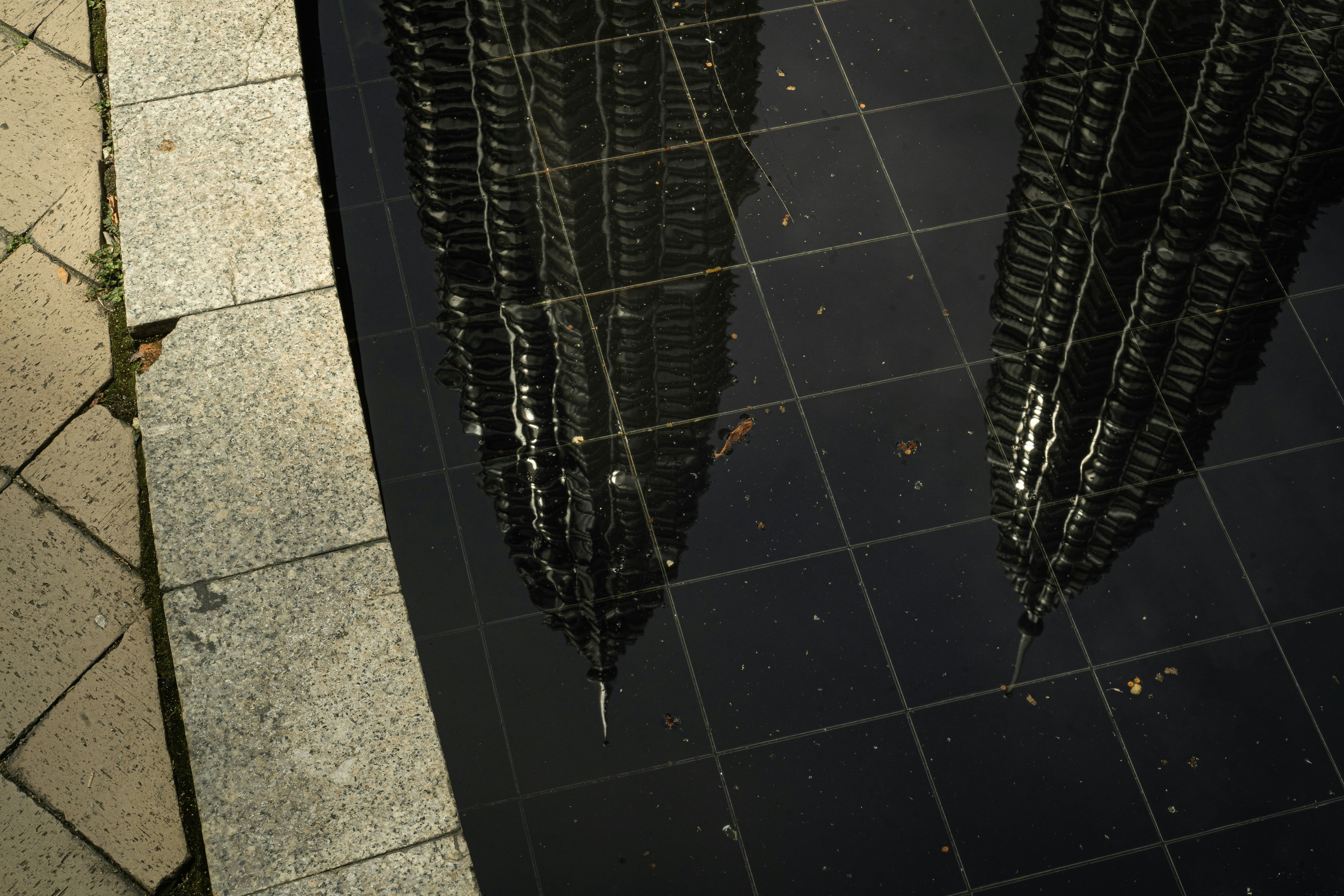 Twin skyscrapers reflected in a wet, tiled surface.