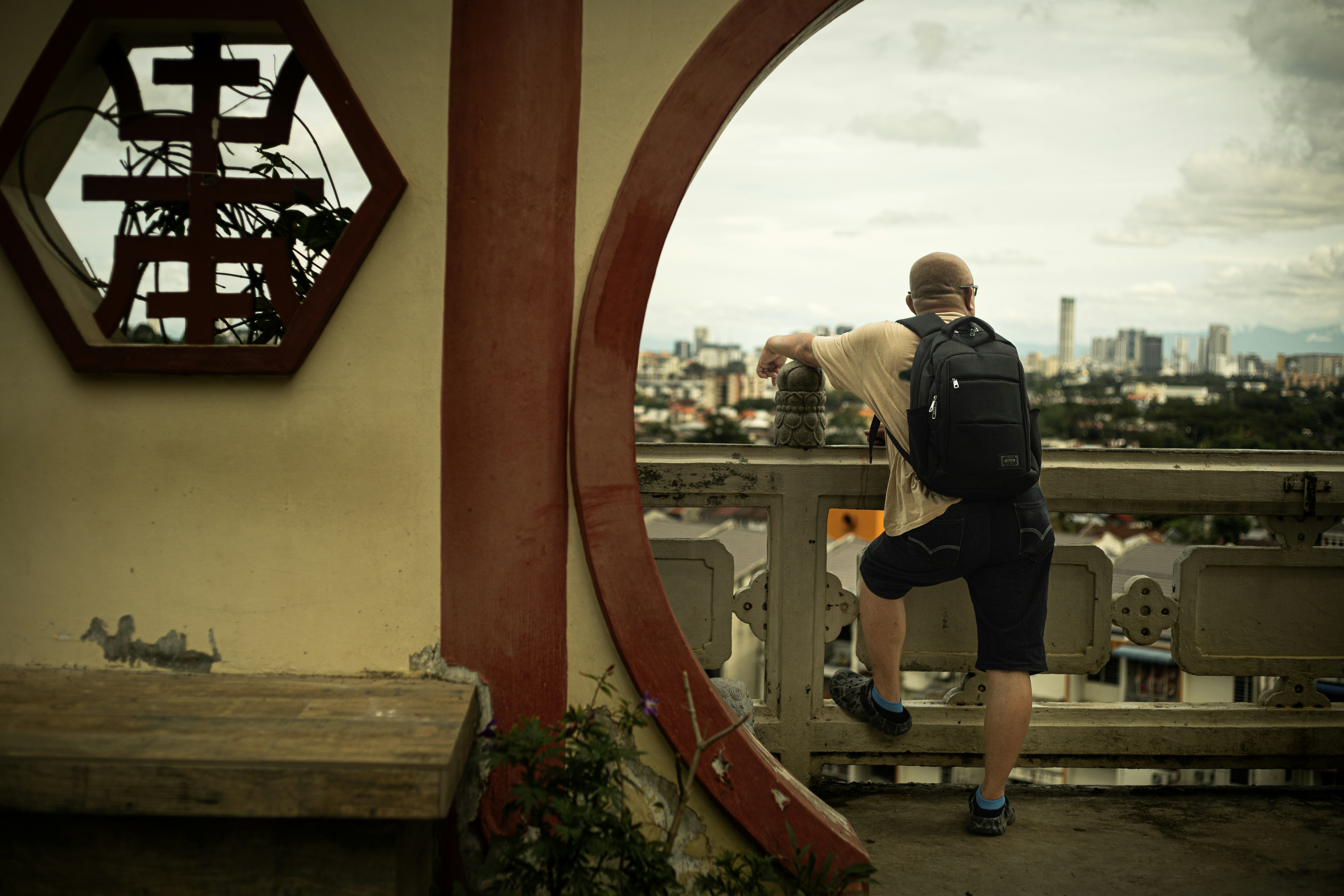 Man with backpack looking at cityscape from a balcony