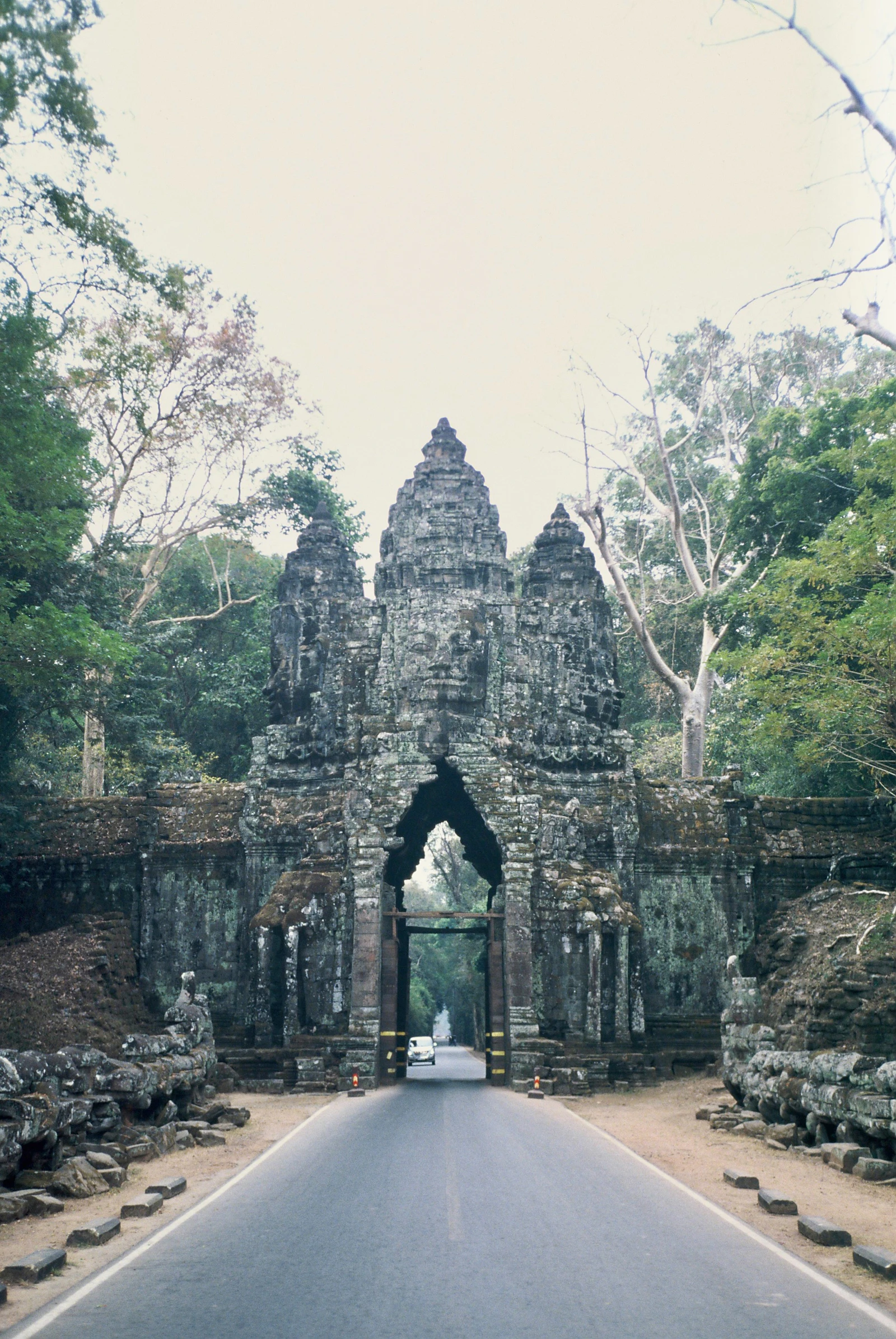 An old stone gate on a road through the Angkor landscape
