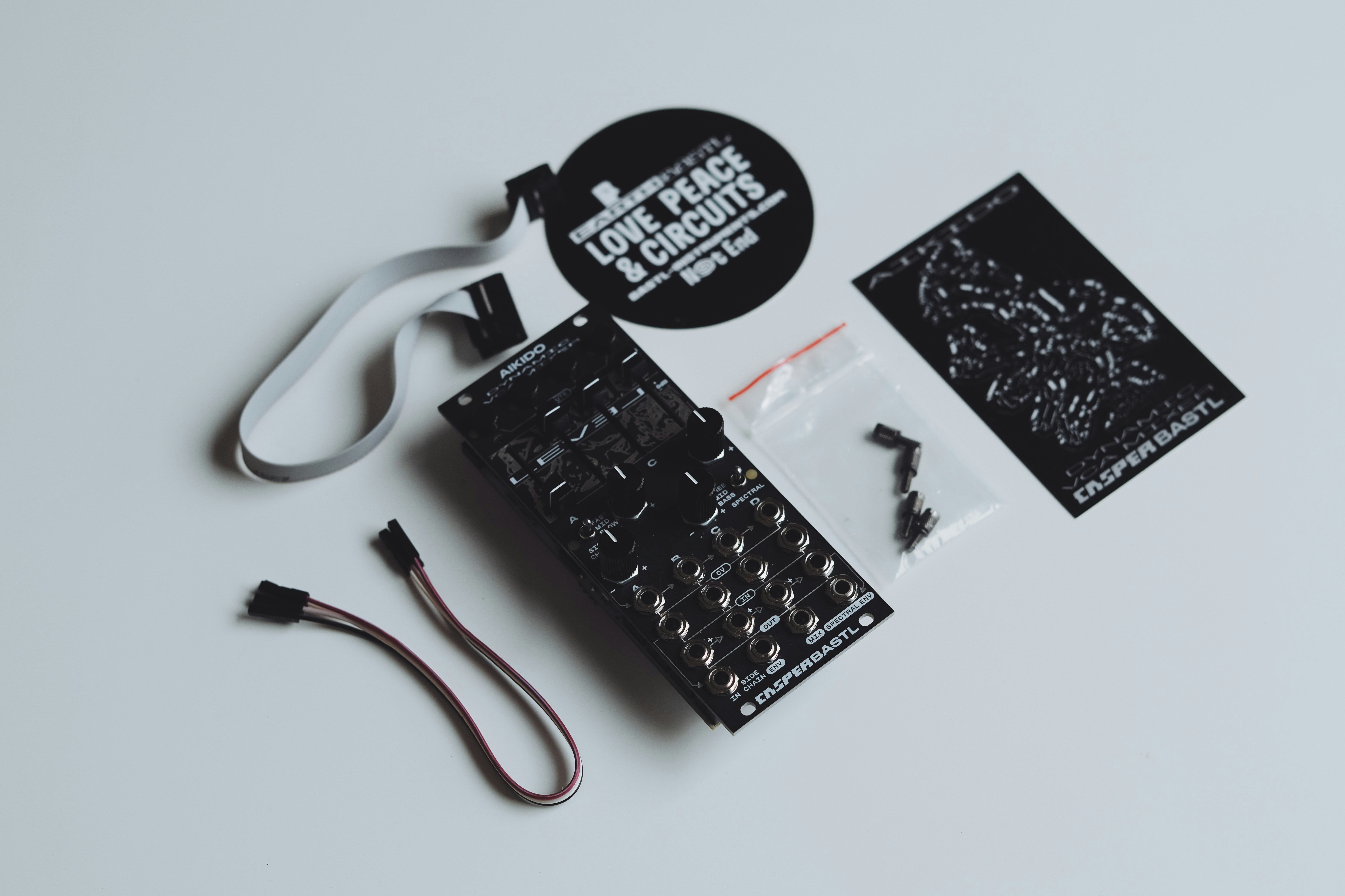 Schwarze elektronische Leiterplatte mit Zubehör auf weißem Hintergrund.