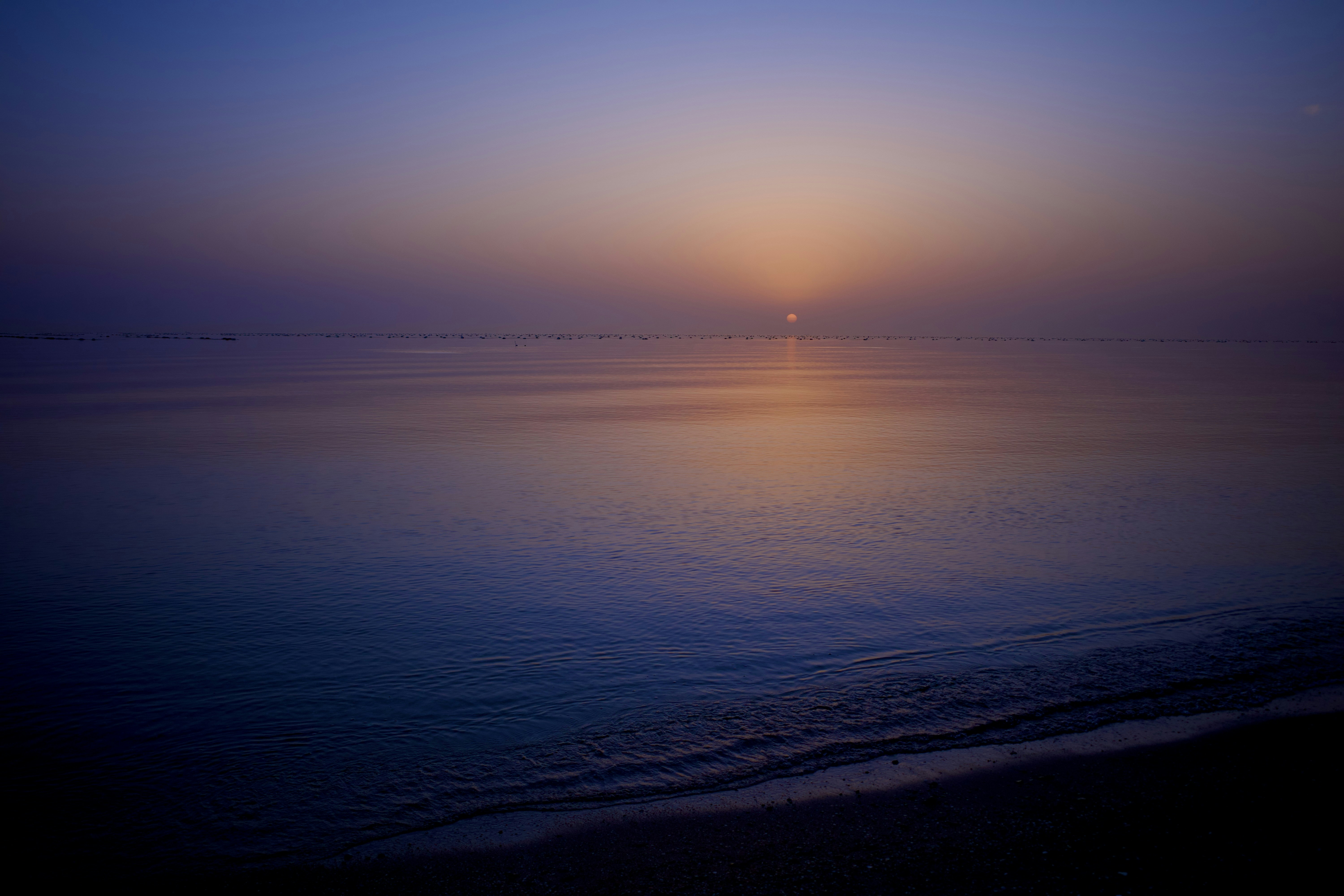 Sunrise over a calm, misty ocean horizon