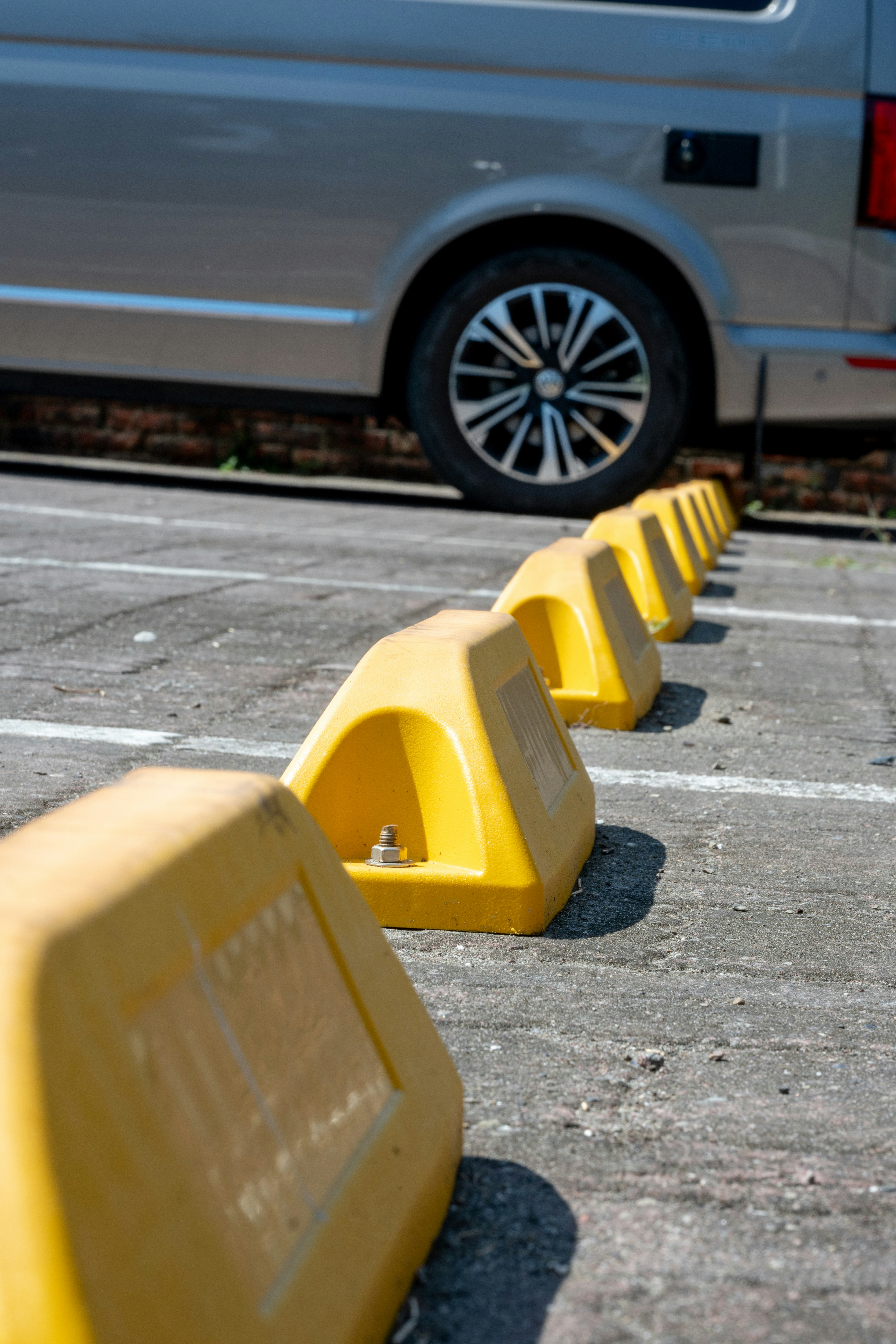 Yellow parking bollards line a paved lot
