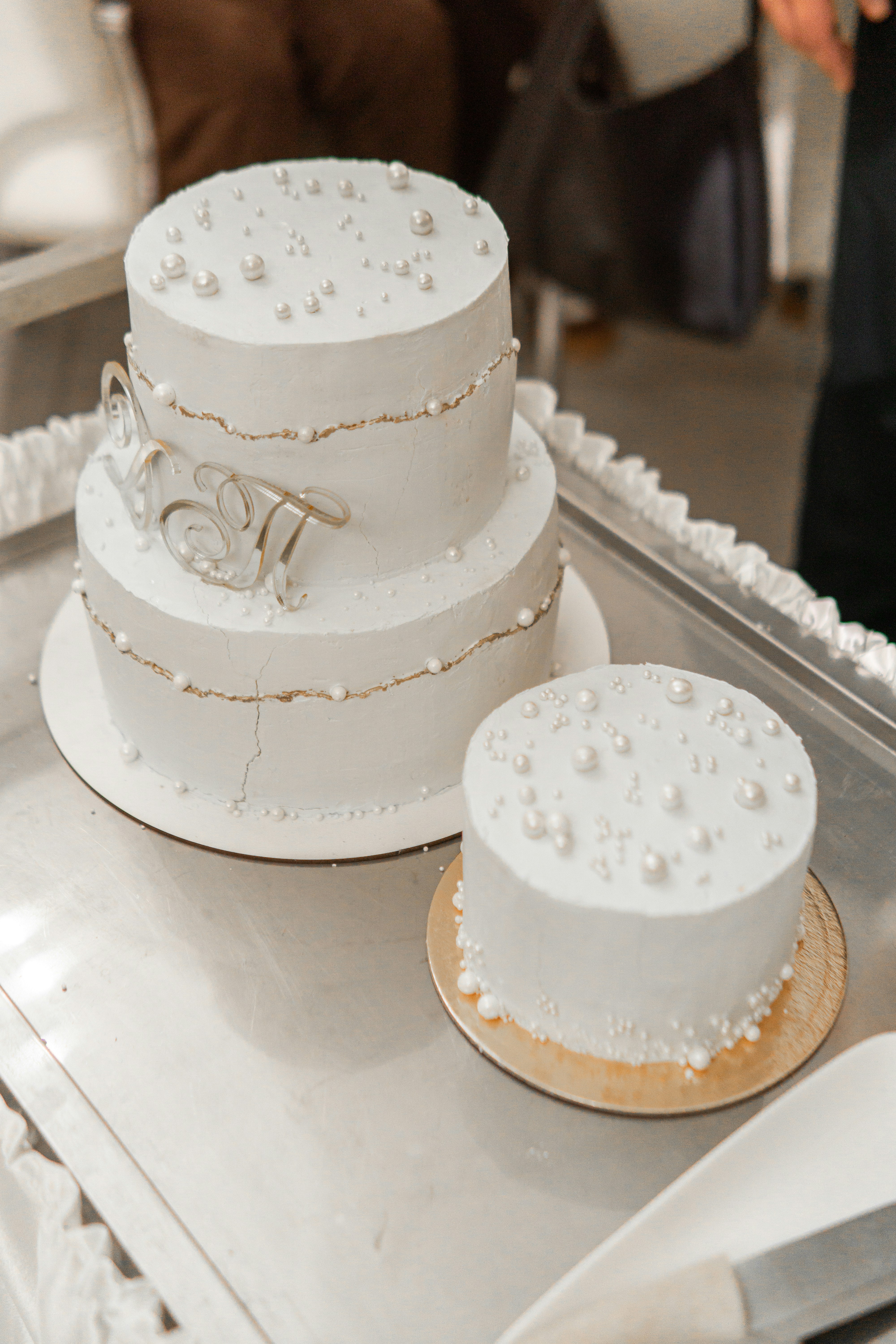 Three-tier white wedding cake with pearls and gold trim