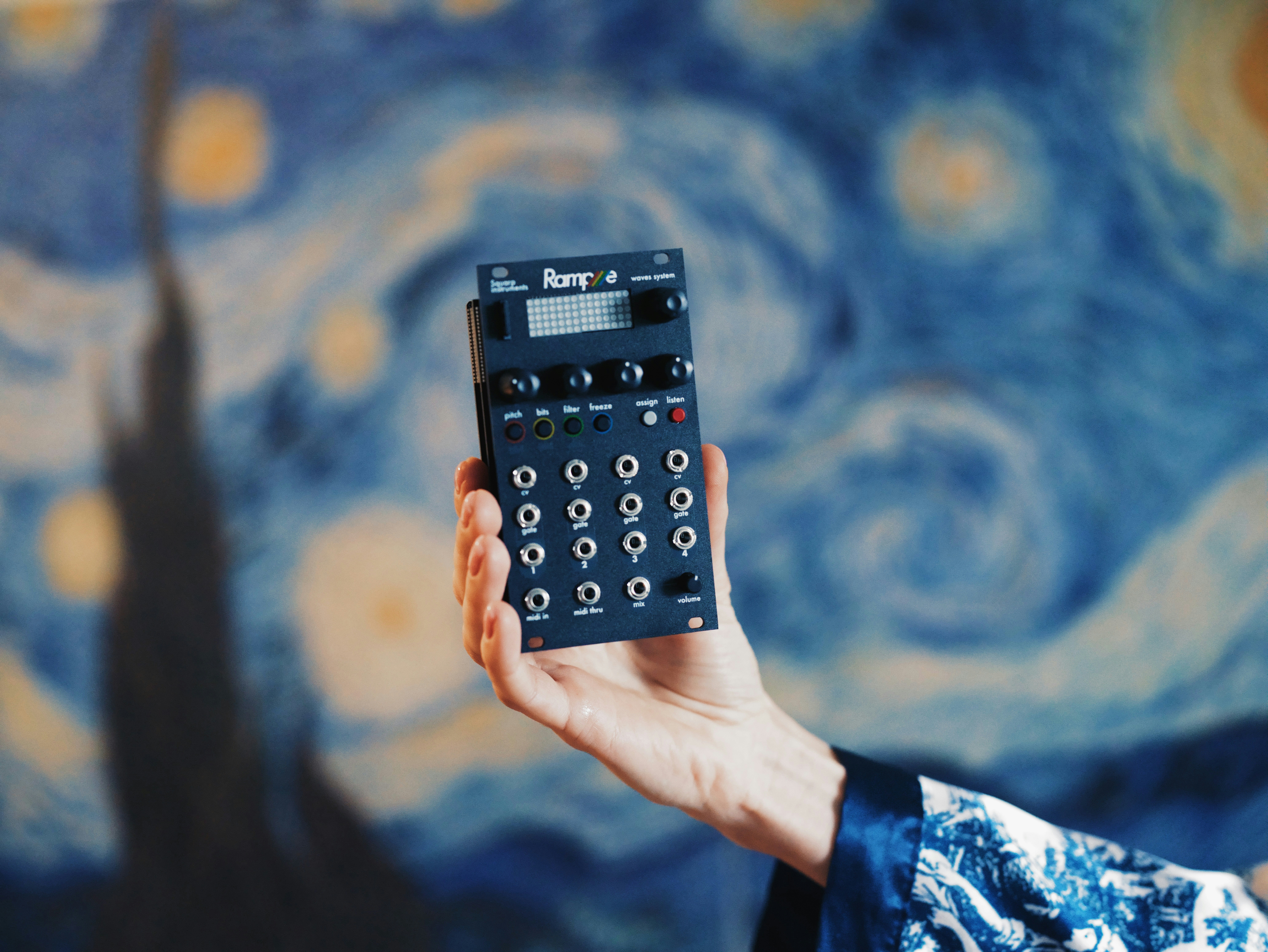 Hand holding a small electronic music device.