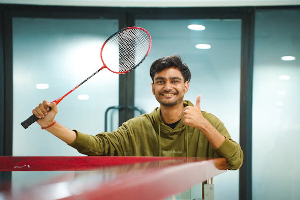 Man holding a badminton racket and giving a thumbs up