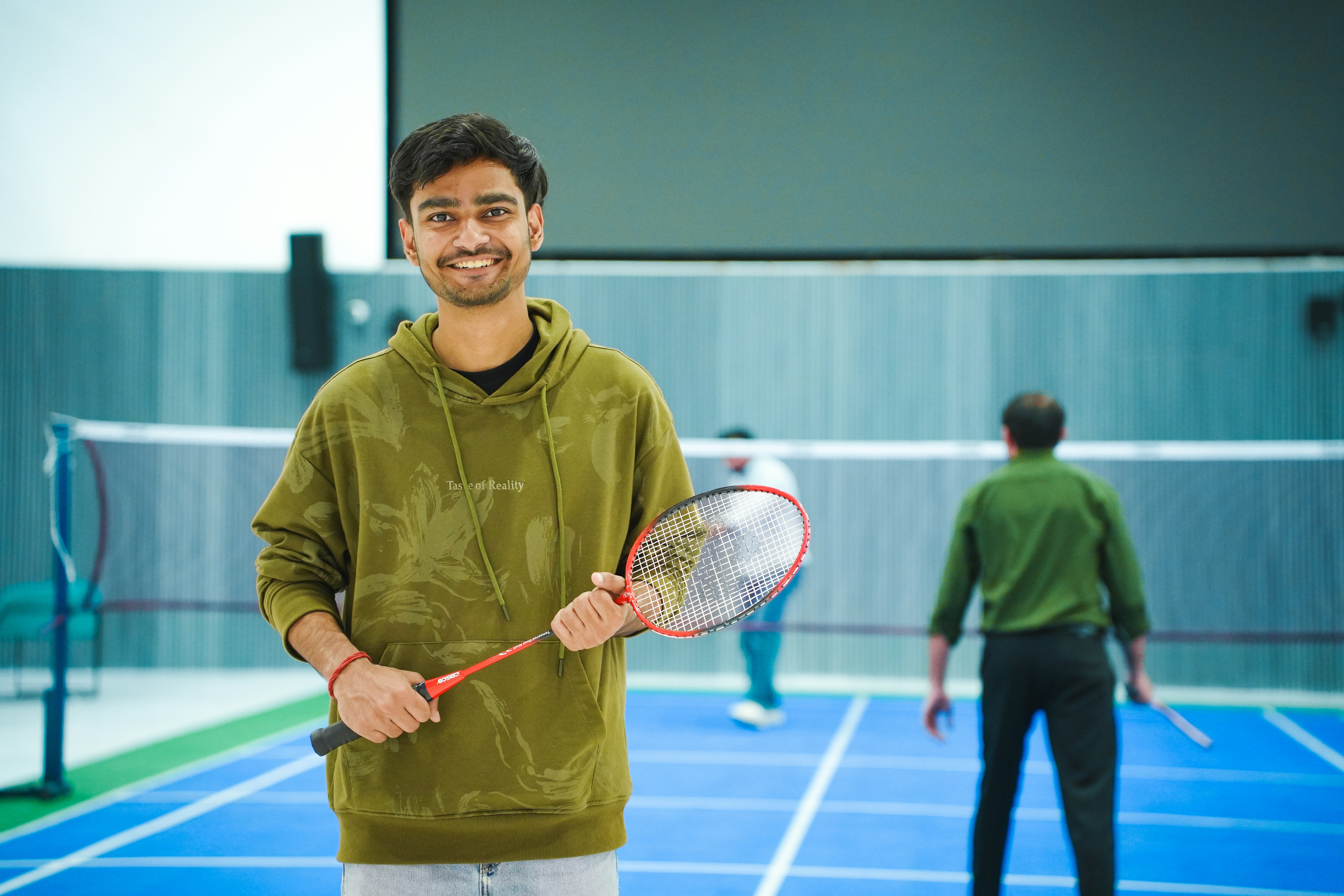 Jeune homme tenant une raquette de badminton sur le court