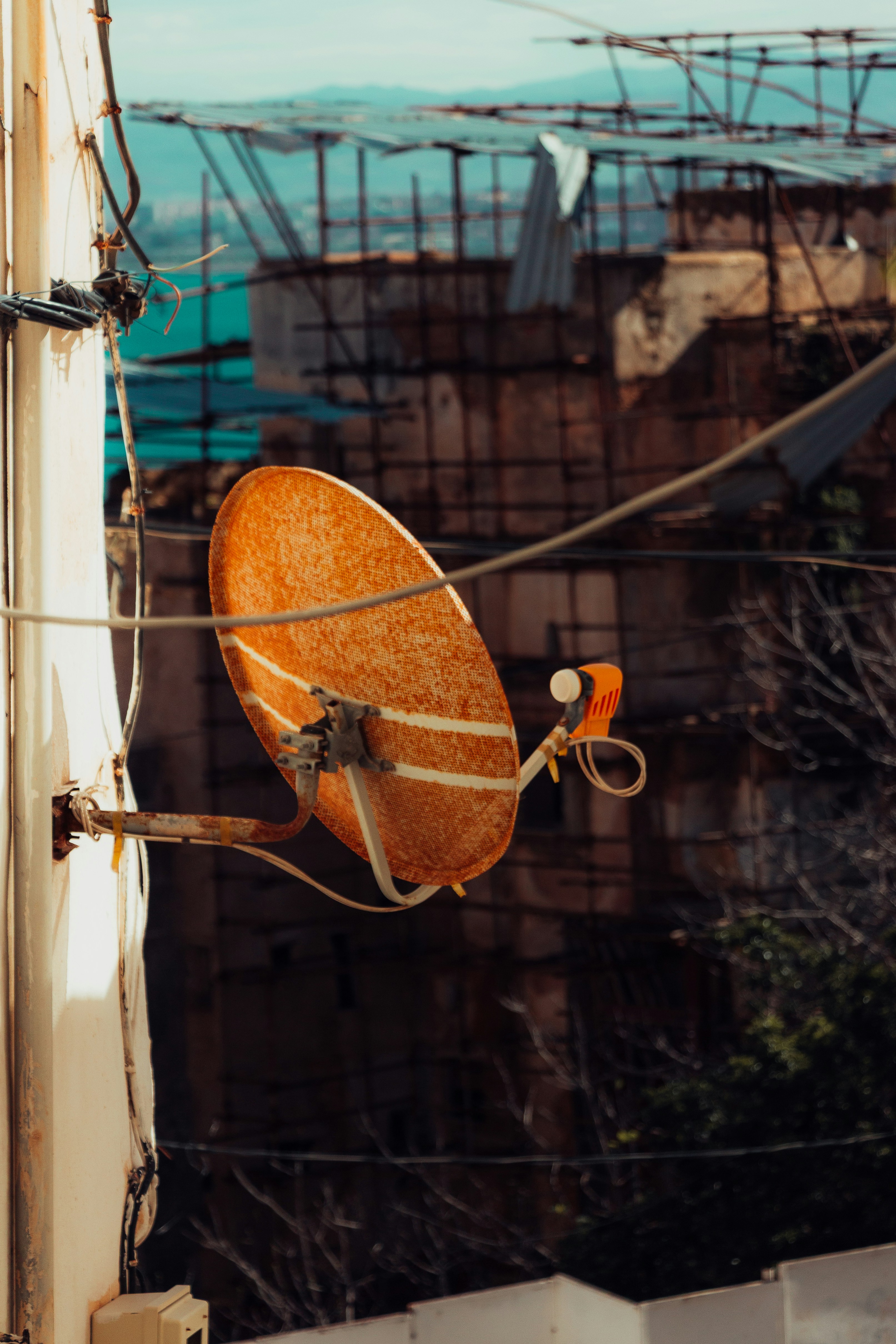 壁に取り付けられた古いオレンジ色の衛星アンテナ。