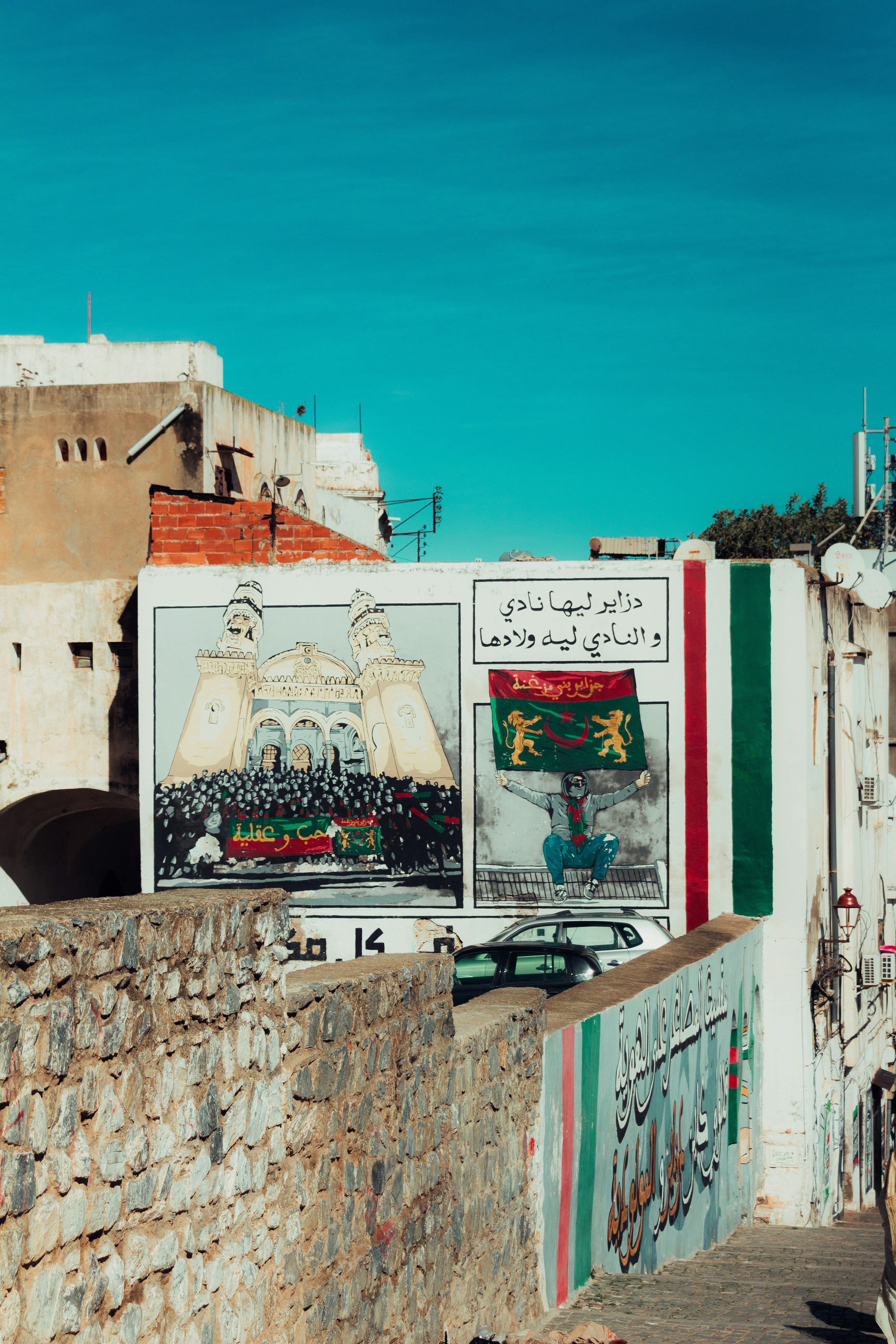 Wandgemälde, das ein historisches Ereignis in arabischer Schrift darstellt.