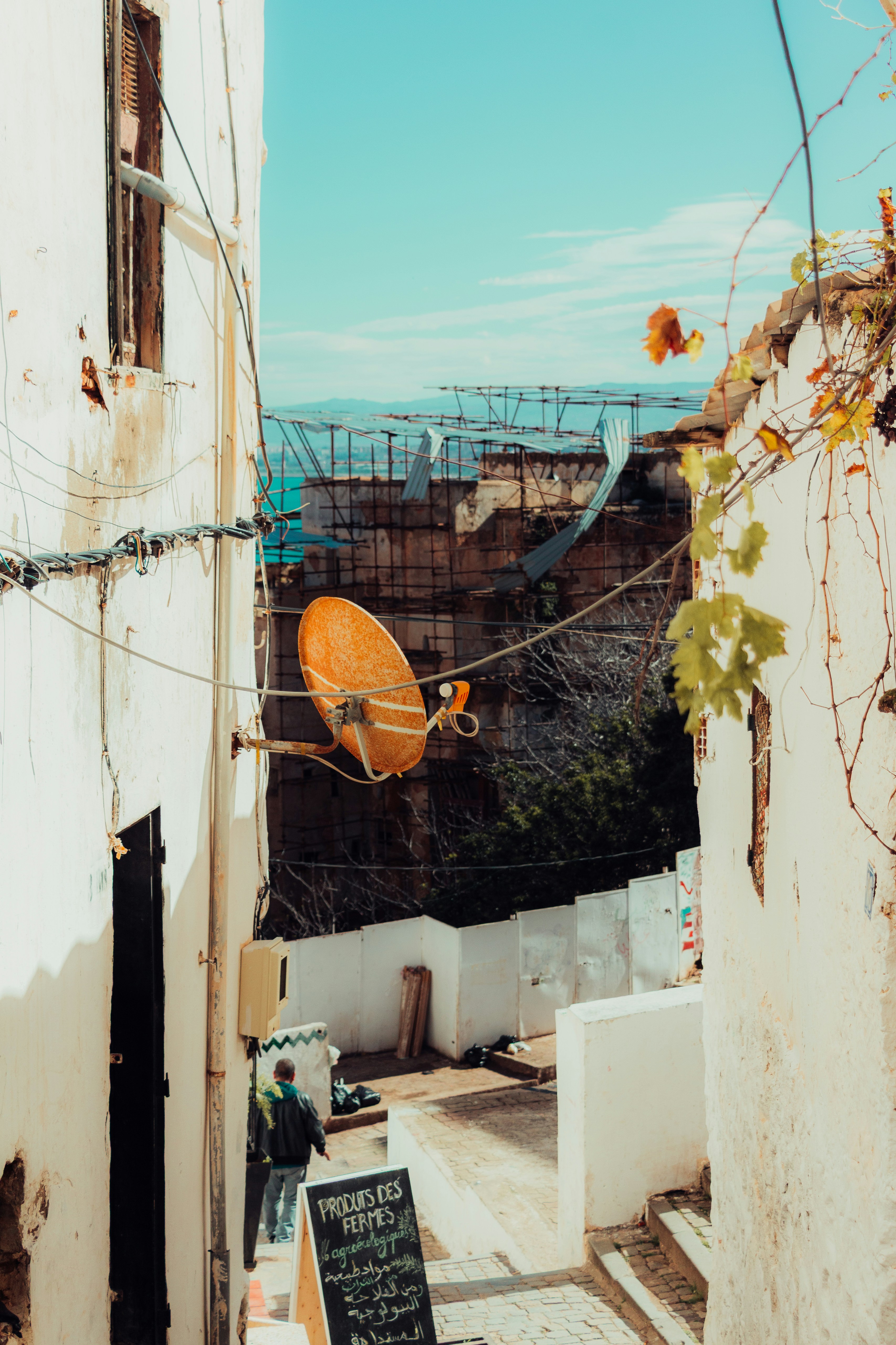 An orange satellite dish on a white building wall.