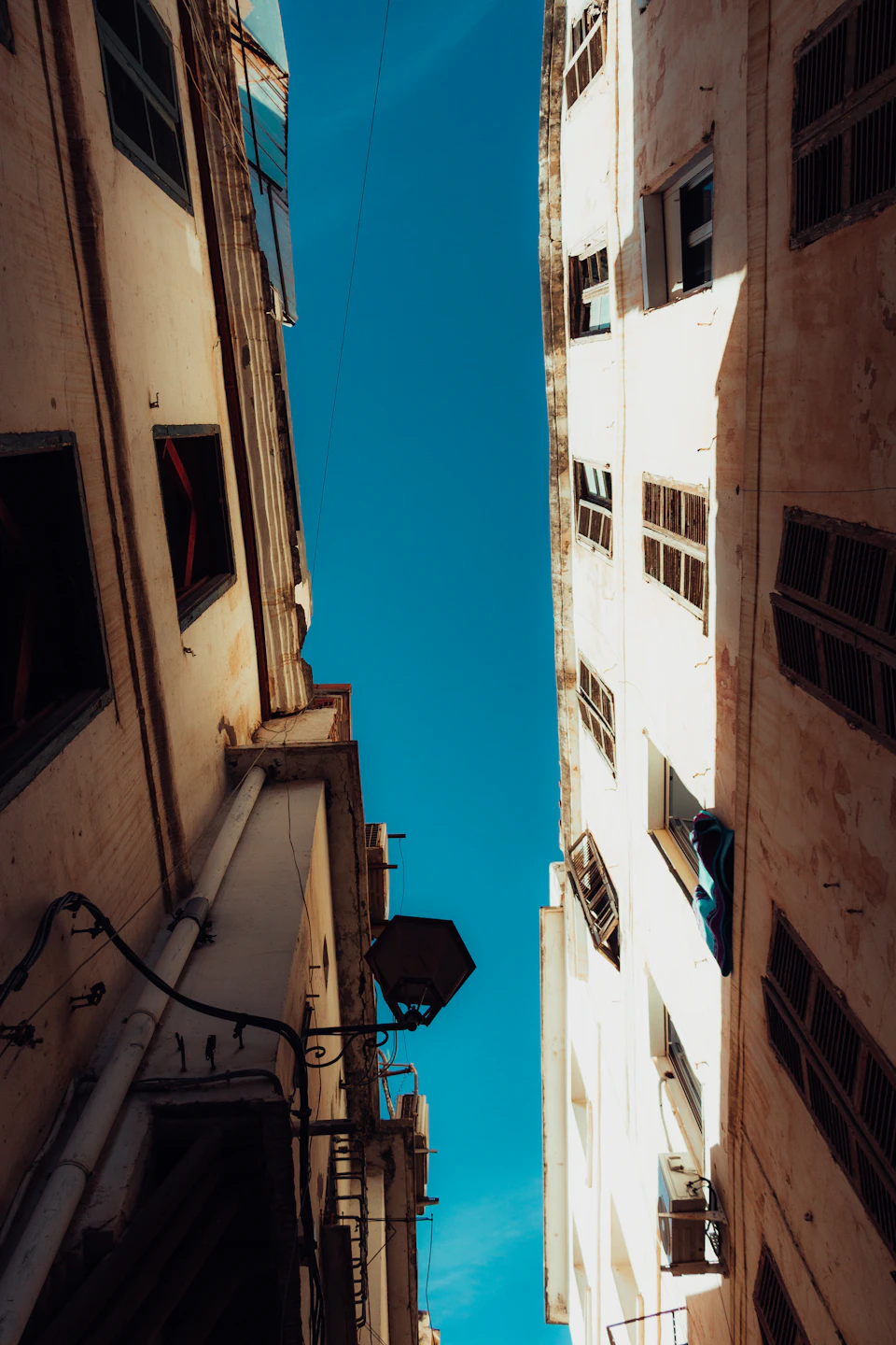 Two white buildings flank a narrow street, one with a small antenna and shutters
