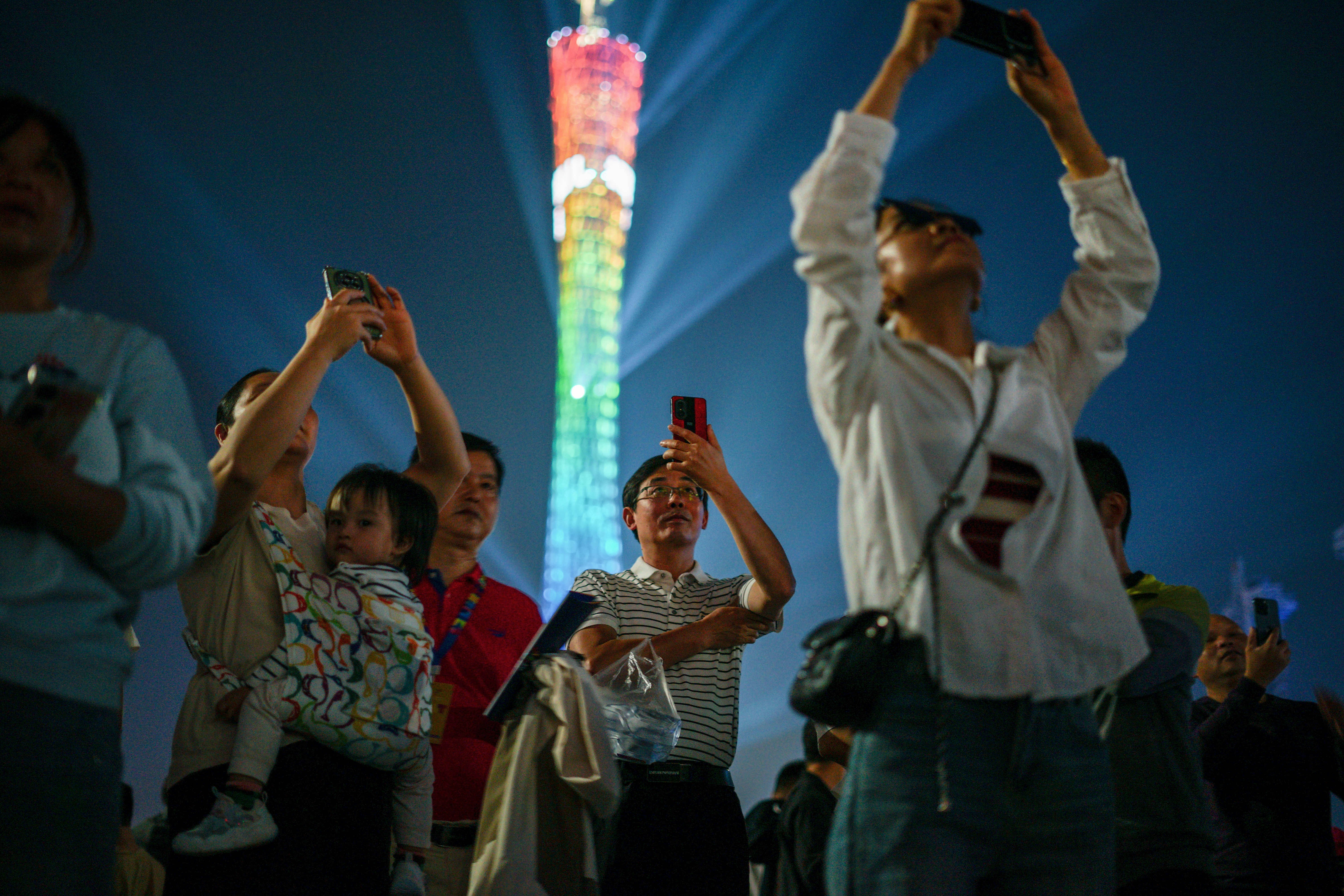people watching a colorful tower light show