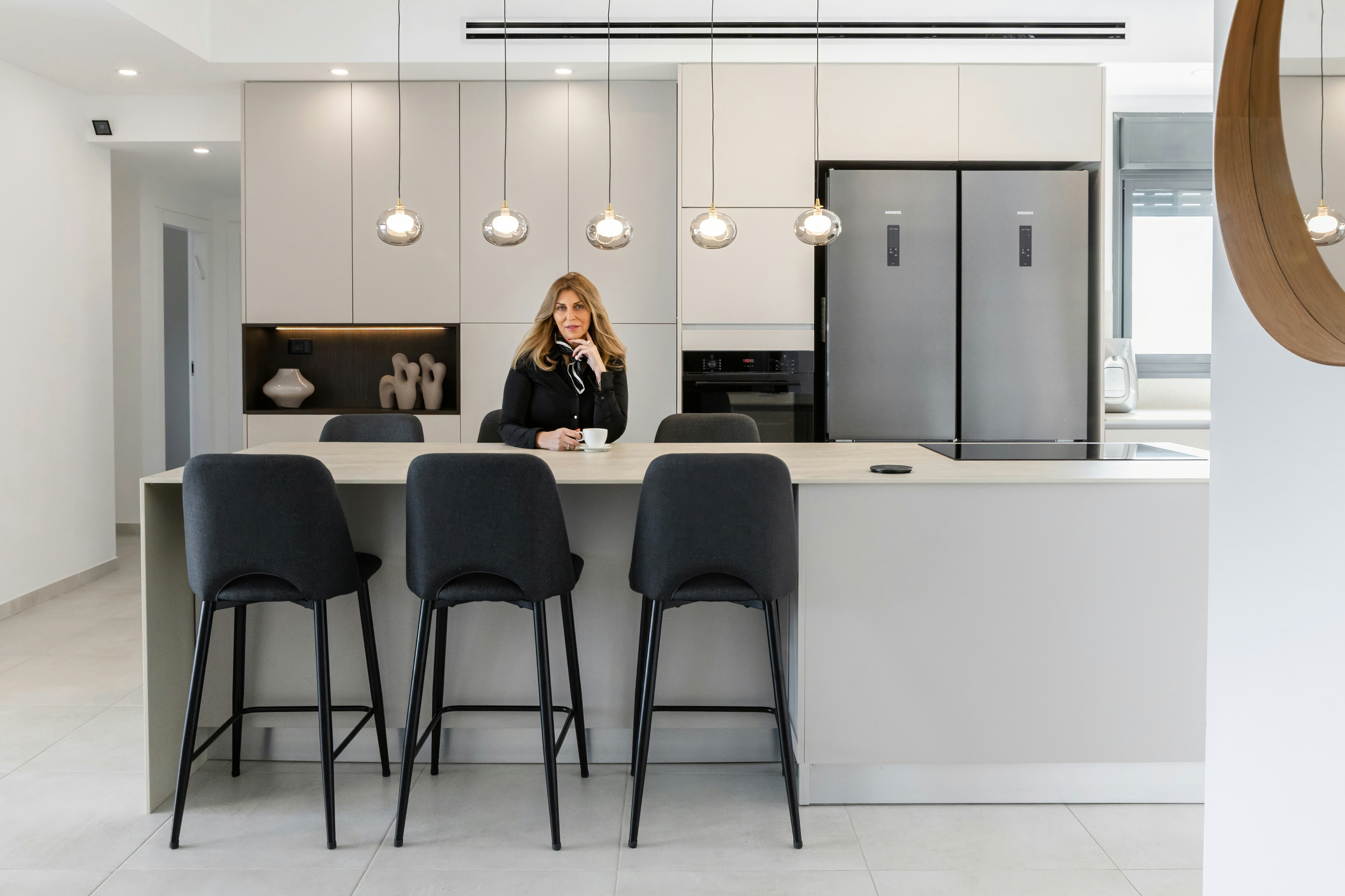 Frau sitzt an einer modernen Kücheninsel mit Barhockern.