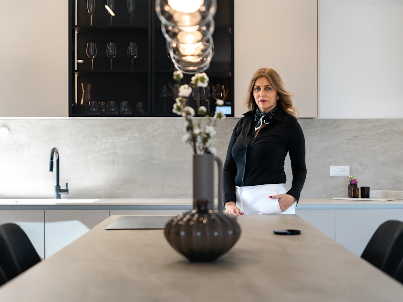 Woman standing in a modern kitchen with island.