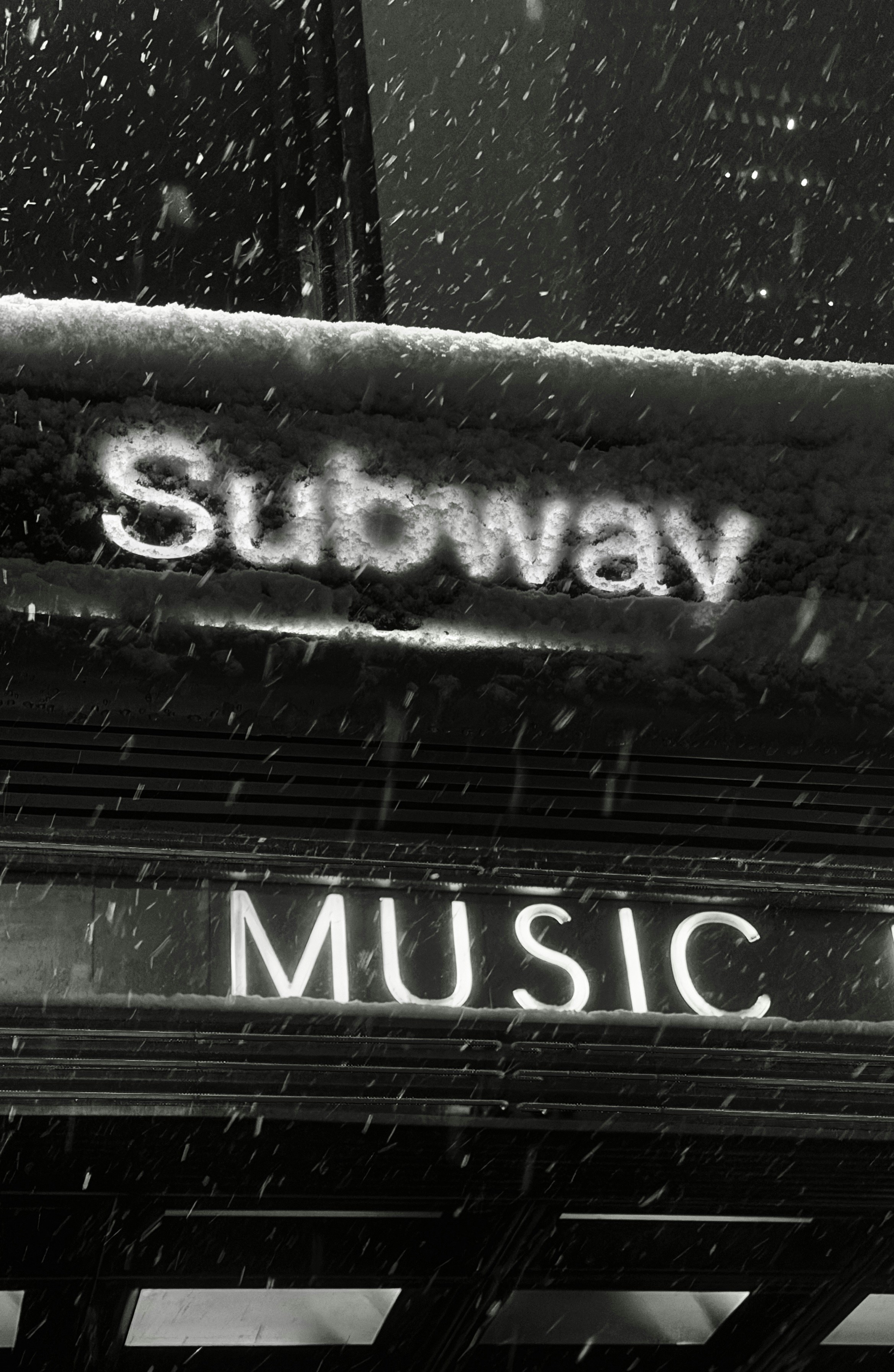 Subway and music signs in falling snow